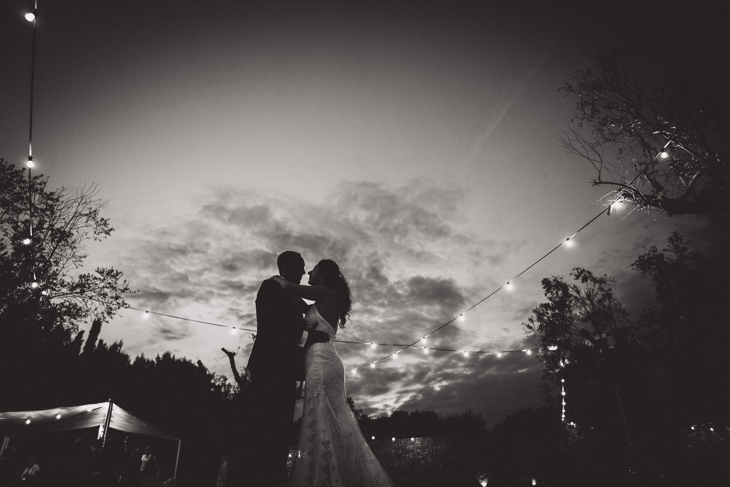 A groom and bride captured in a romantic wedding photo under sparkling string lights.