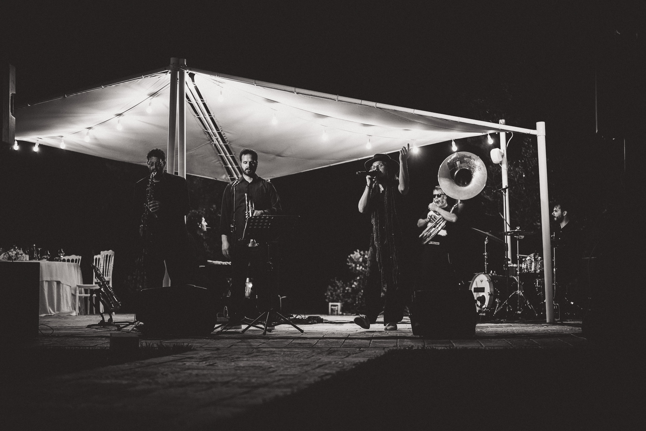 A black and white photo of a band playing at night at a wedding.