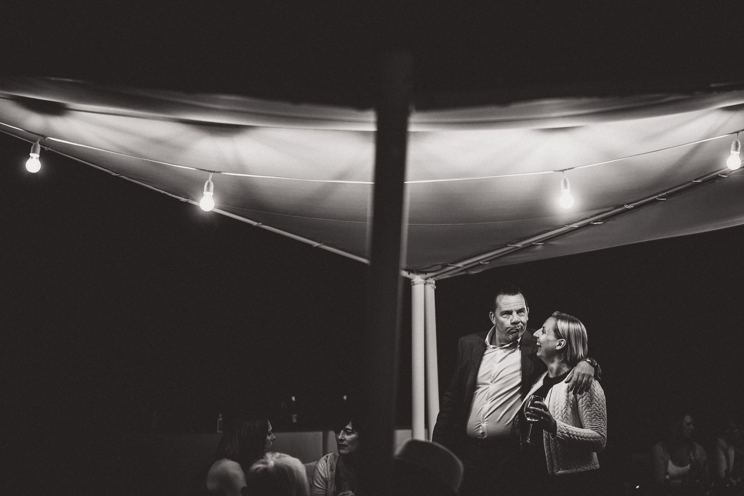 A groom and bride standing under a tent at night.