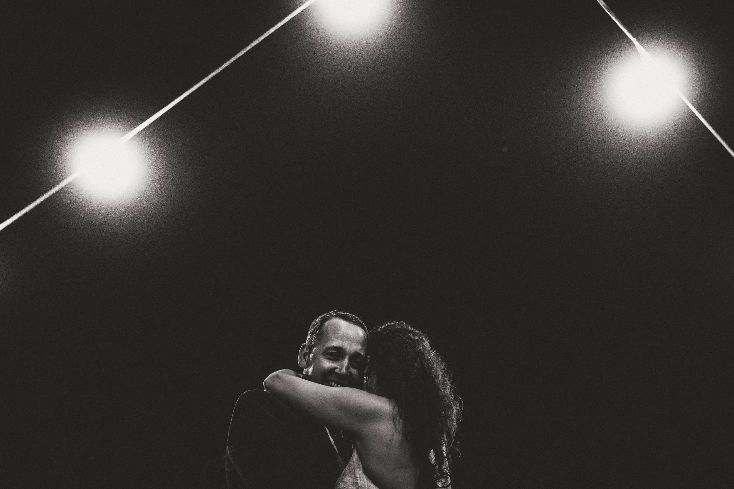 A bride and groom embracing under twinkling lights.