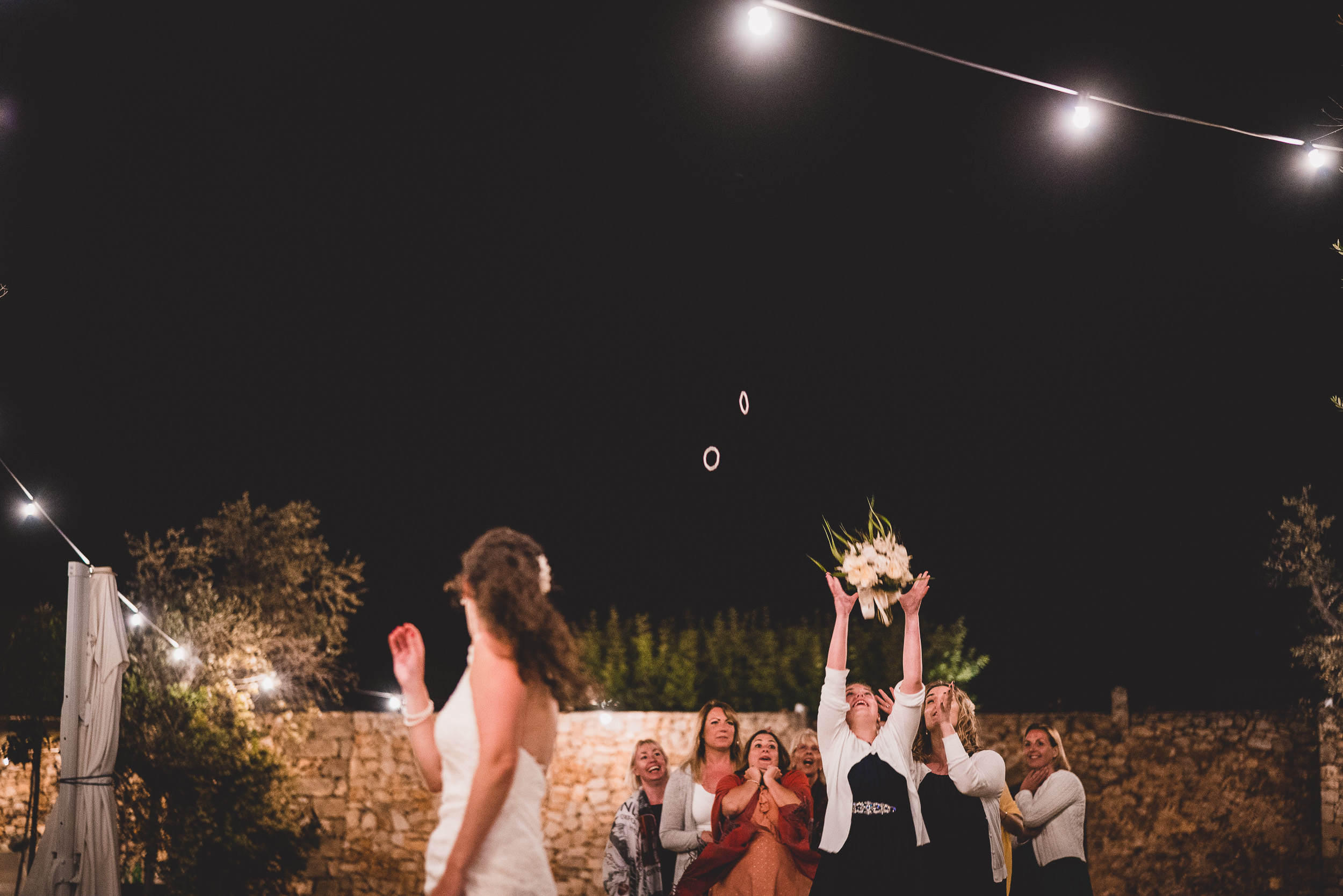 A wedding photo captures the bride and groom joyfully throwing confetti in the air at night.