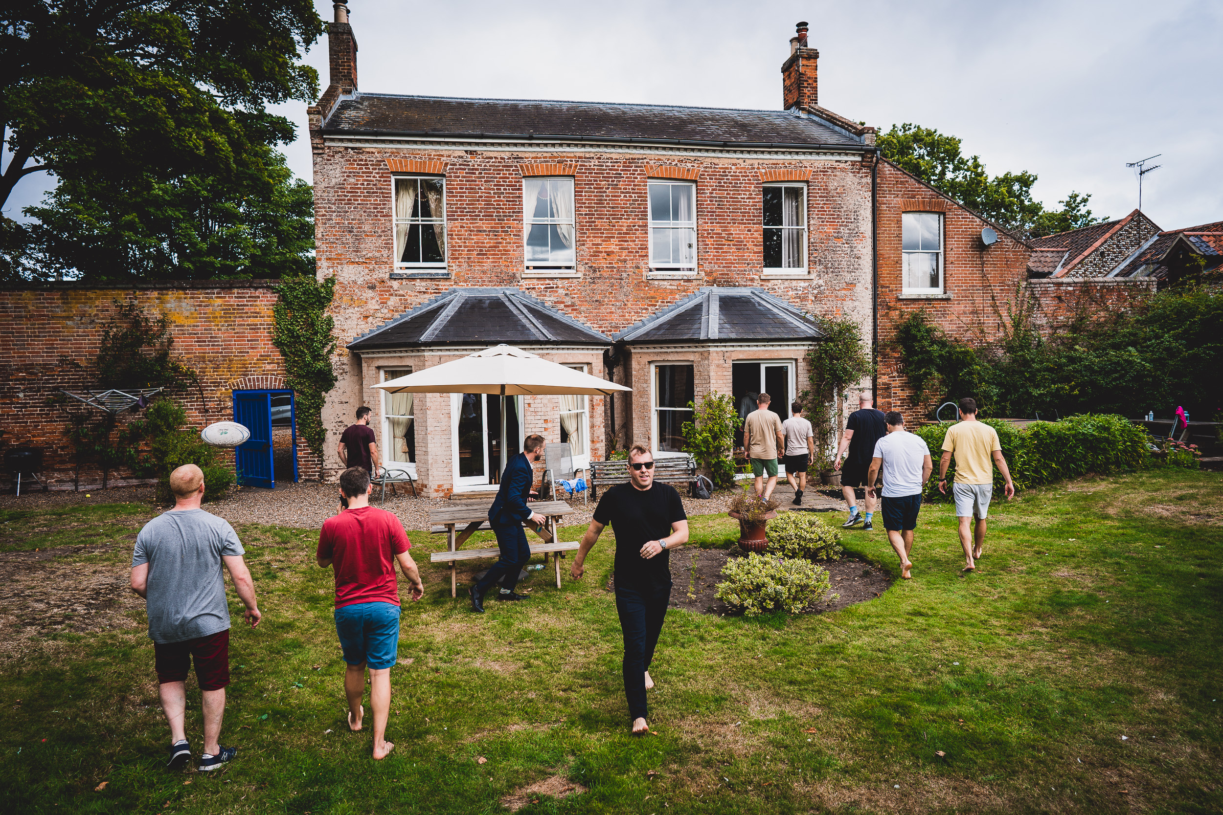 A group of people posing for a wedding photo in front of a house.