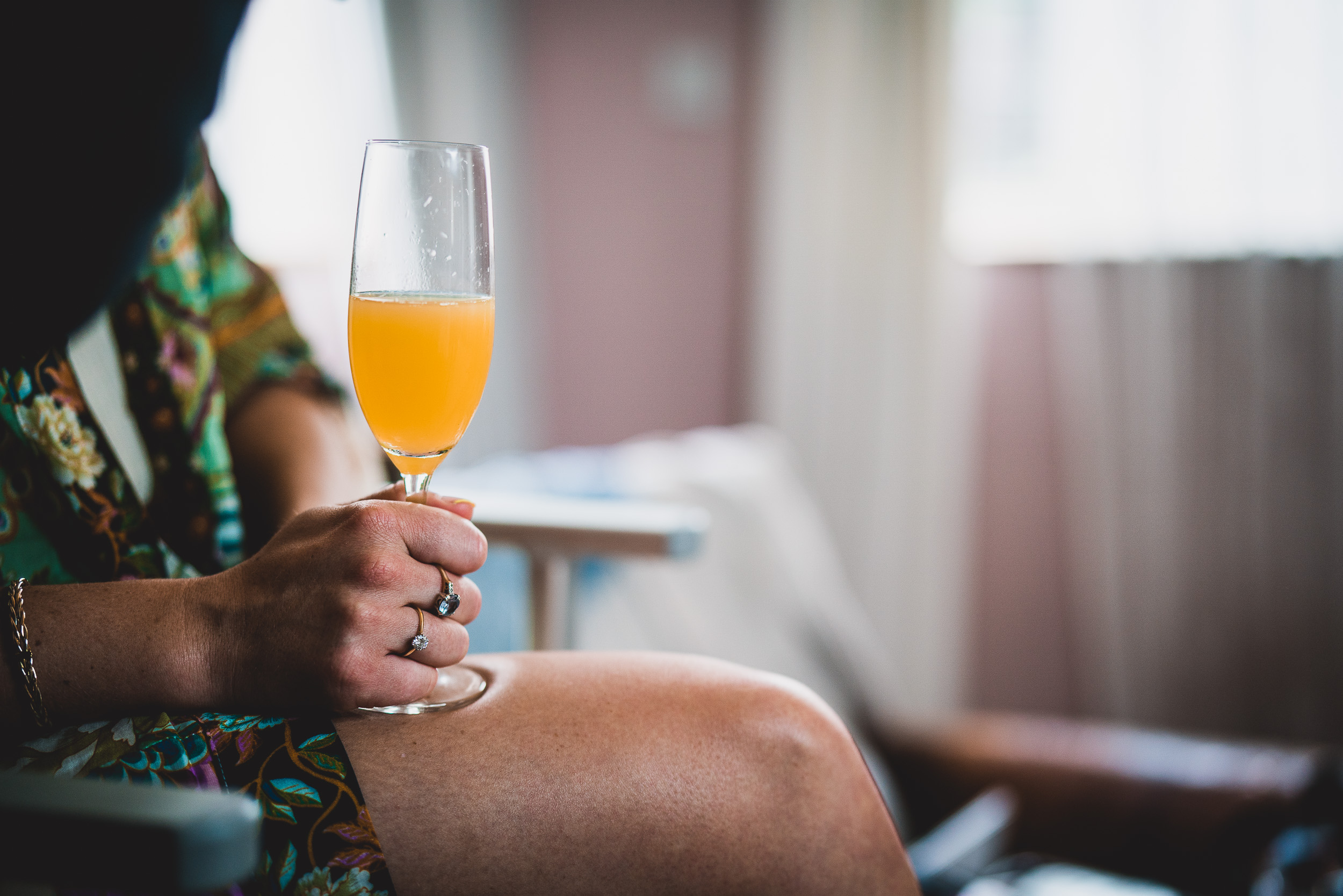 A wedding photographer capturing a woman holding a glass of orange juice in a wedding photo.