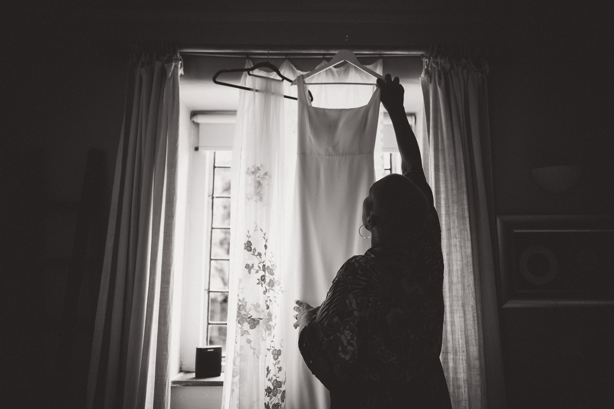 A bride wearing her wedding dress while being photographed in front of a window.