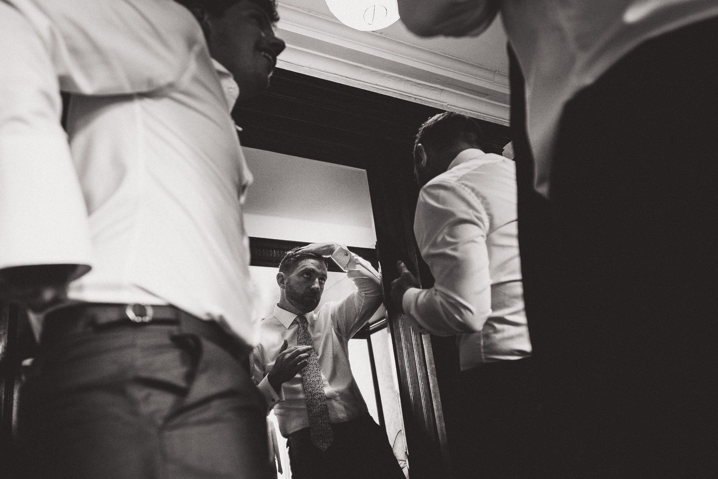 A black and white wedding photo capturing men preparing for the big day.