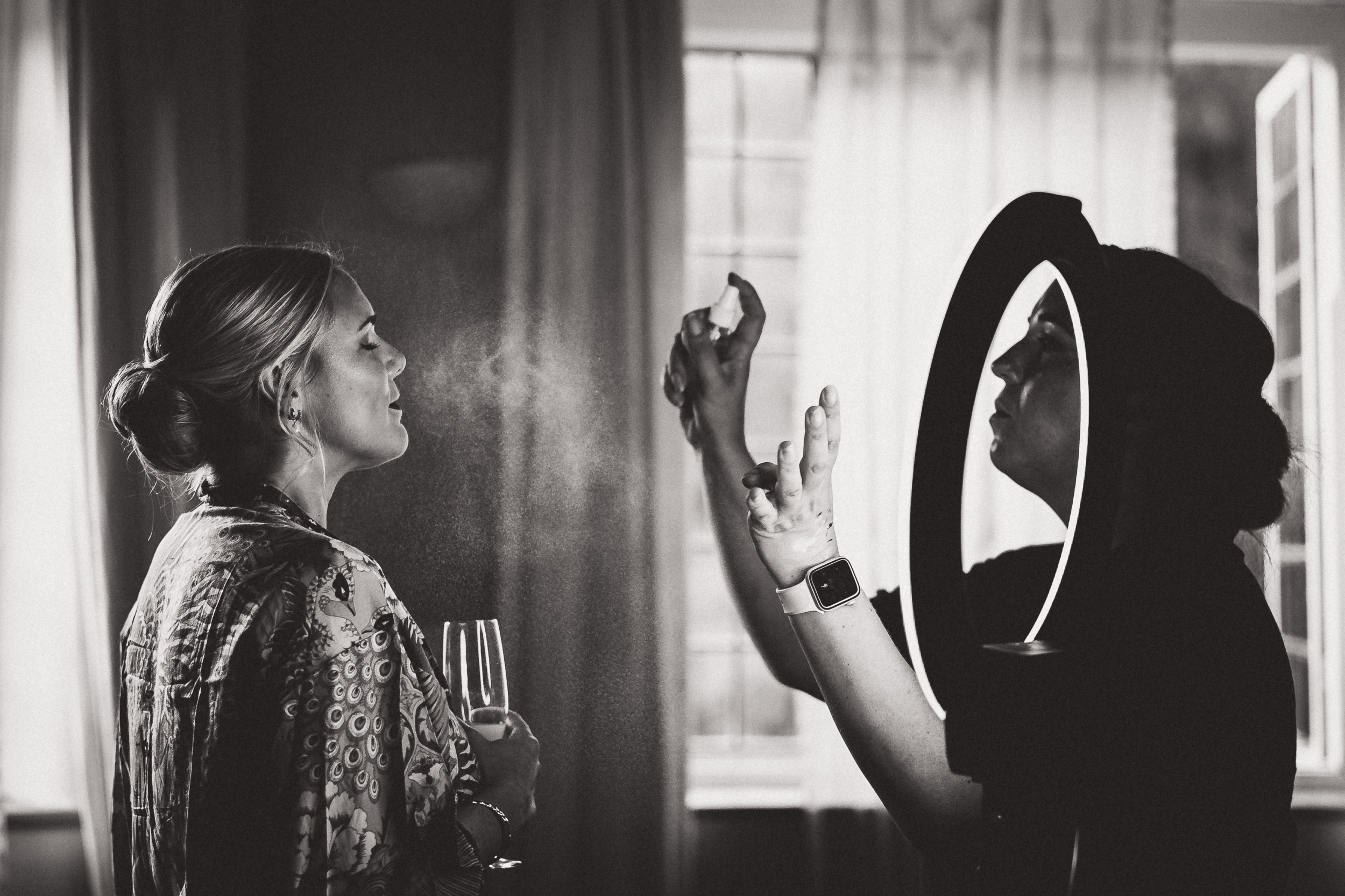 A bride is preparing in front of a mirror for her wedding.