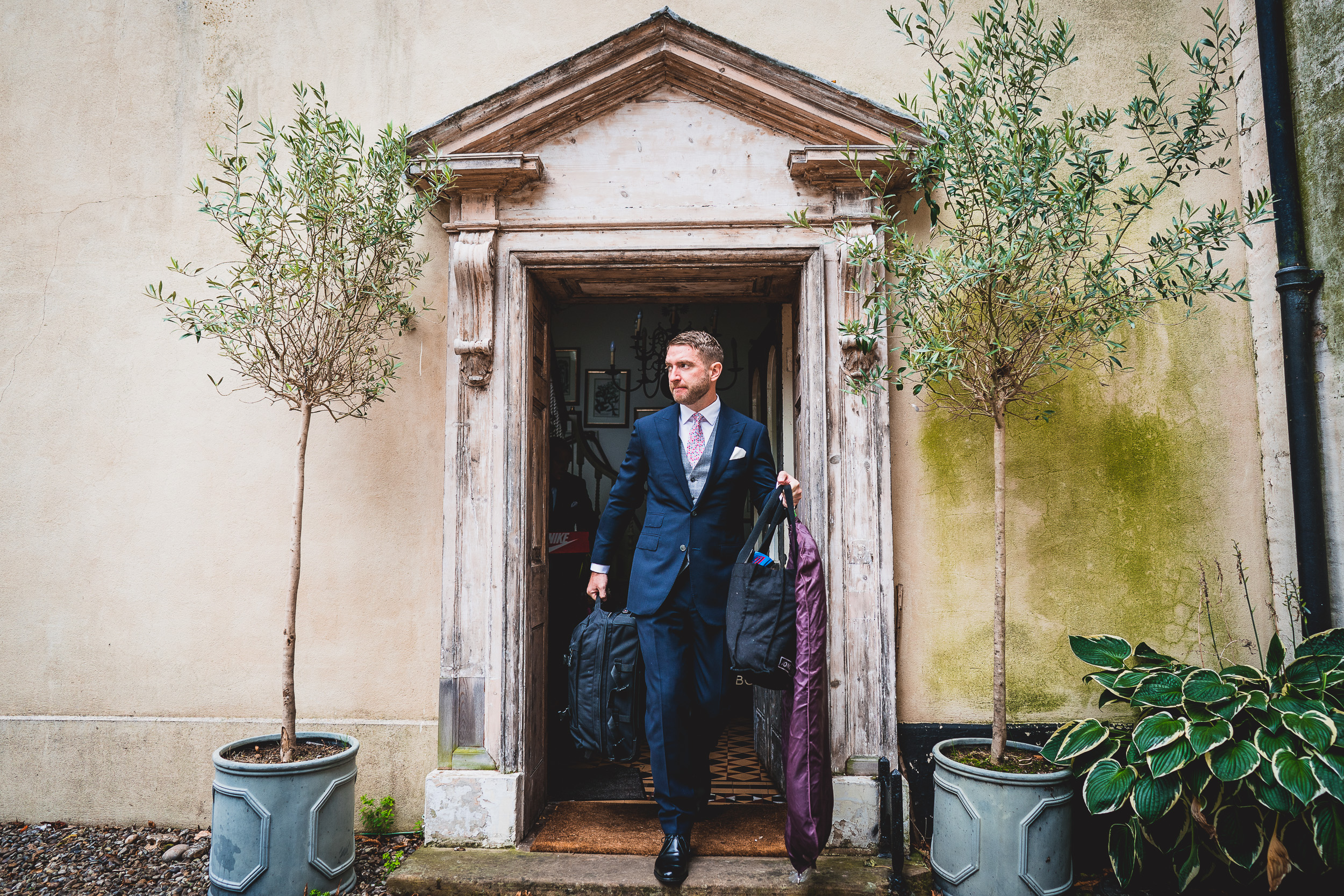 A groom photographed by a wedding photographer in his suit at the entrance.