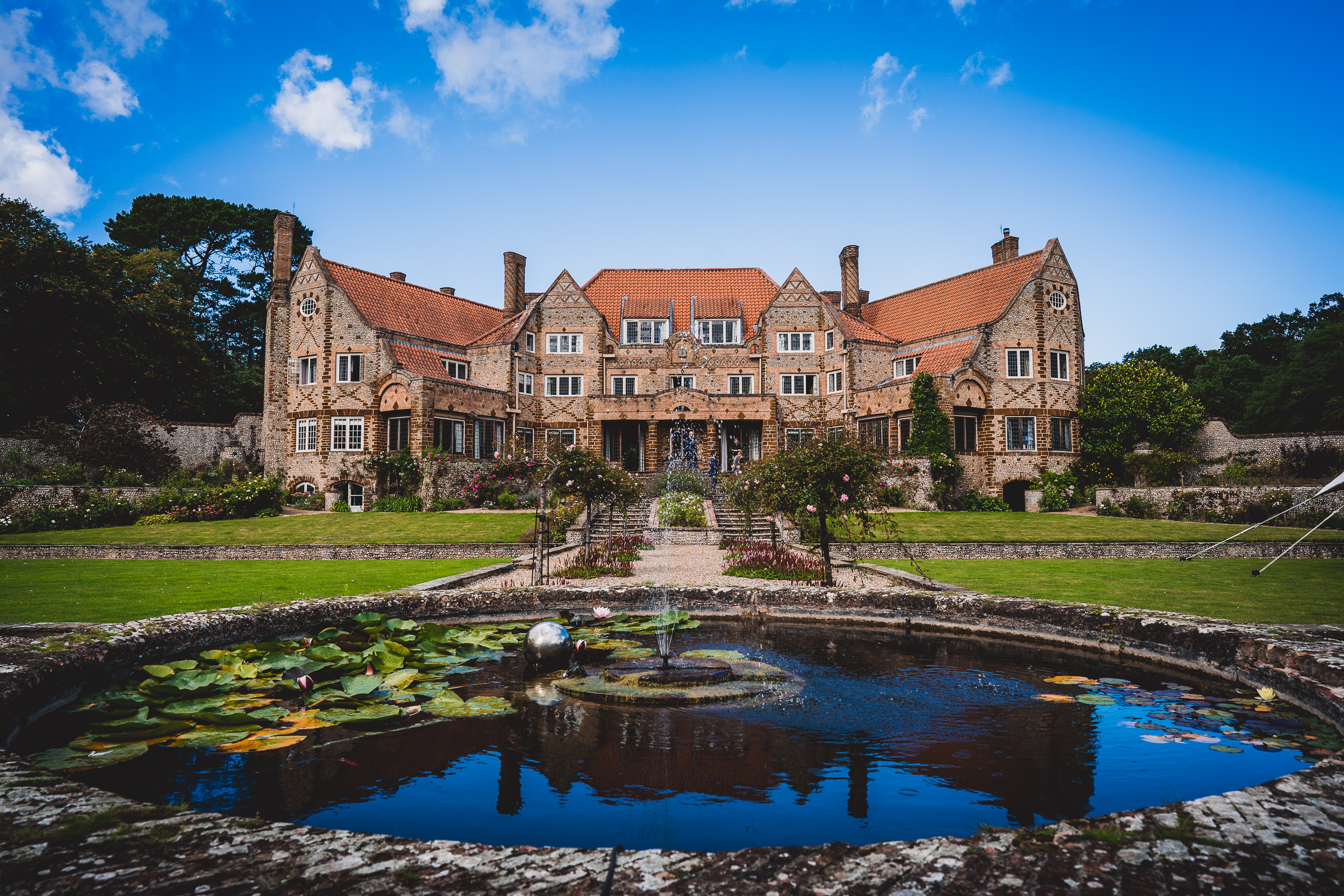 A grand mansion with a picturesque pond, perfect for capturing stunning wedding photos.