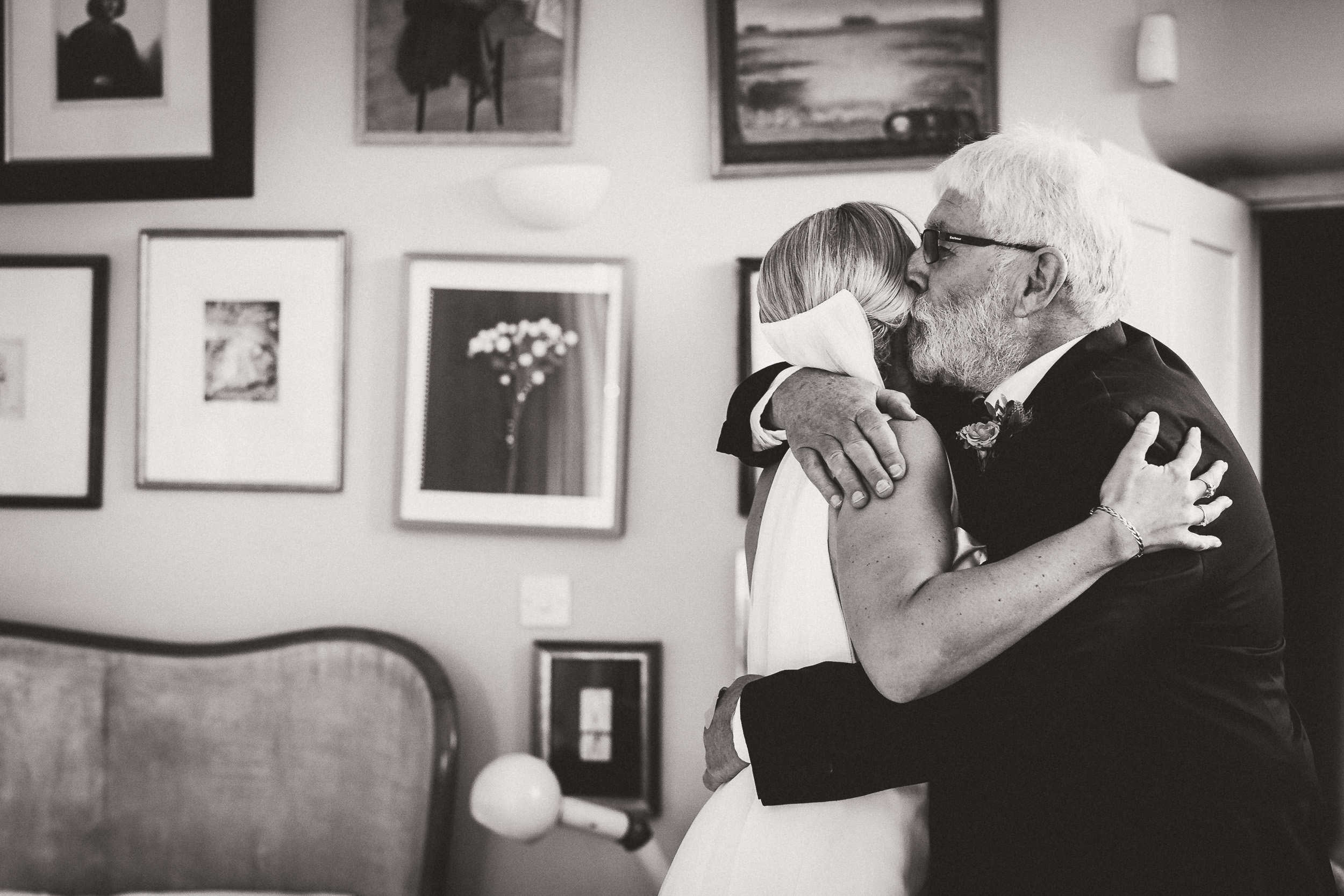 A bride embracing her father in a black and white wedding photograph.