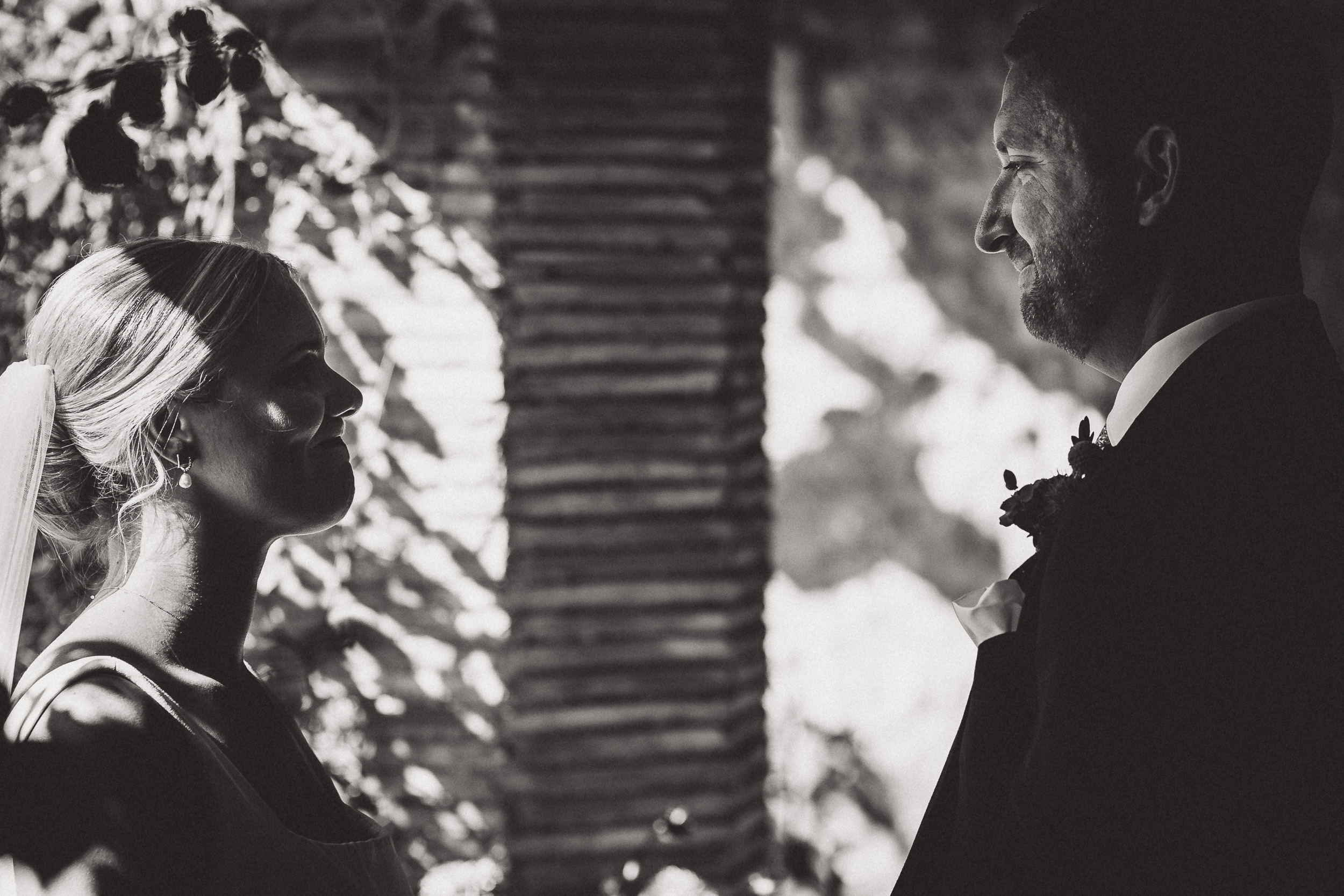 A black and white wedding photo capturing the joyful gaze between a bride and groom.