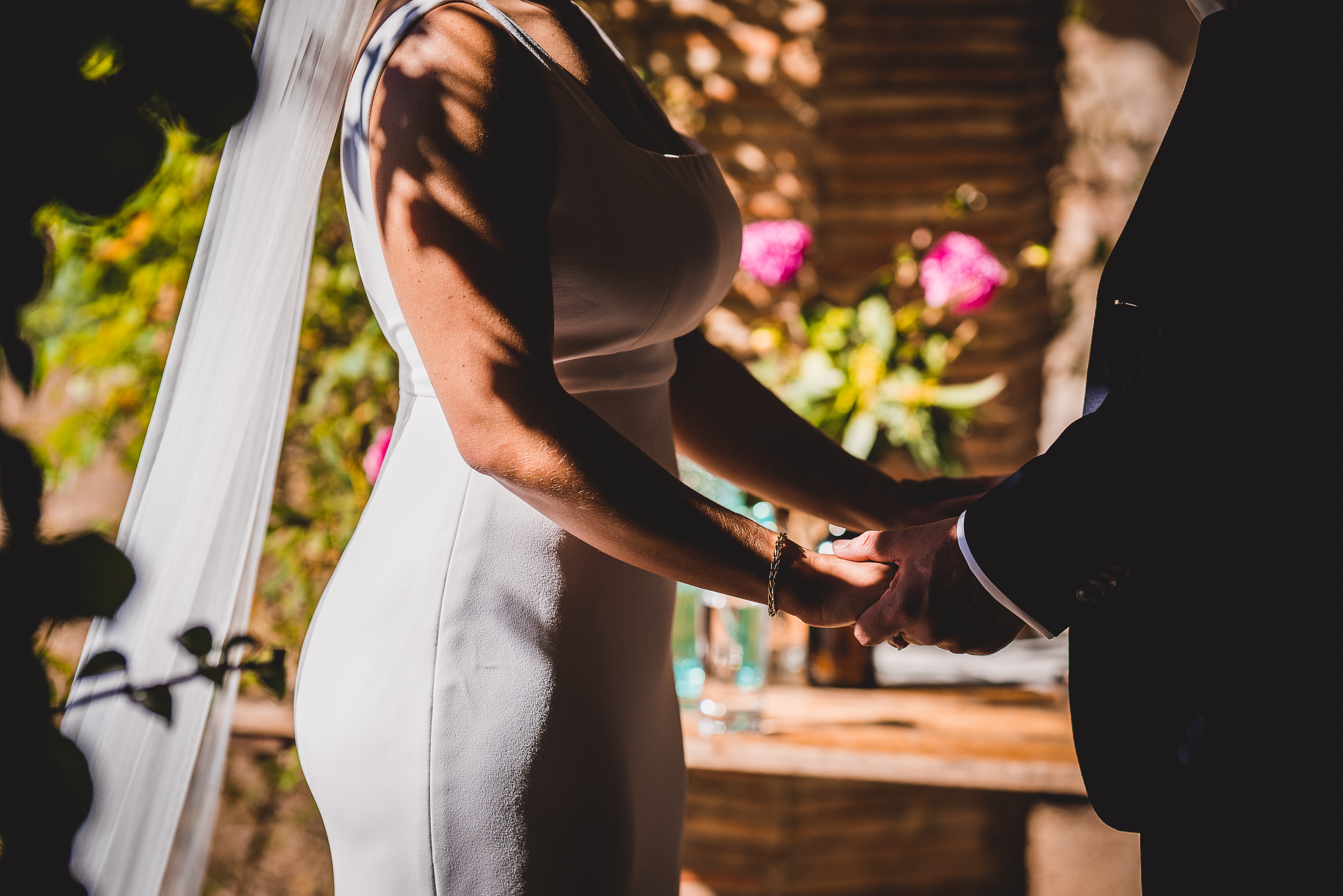 A wedding photo of the groom holding hands with the bride in a garden.