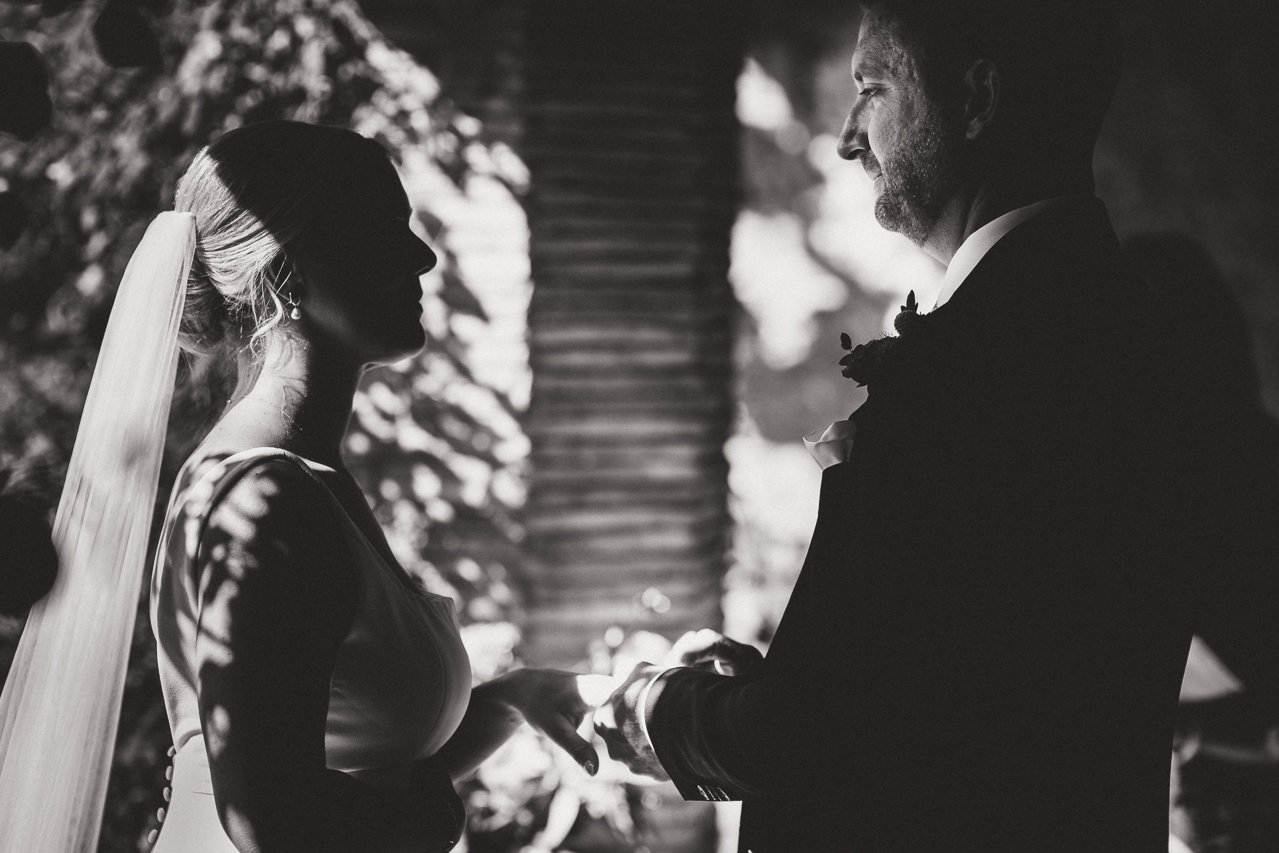 A black and white photo capturing the wedding ceremony of a bride and groom.