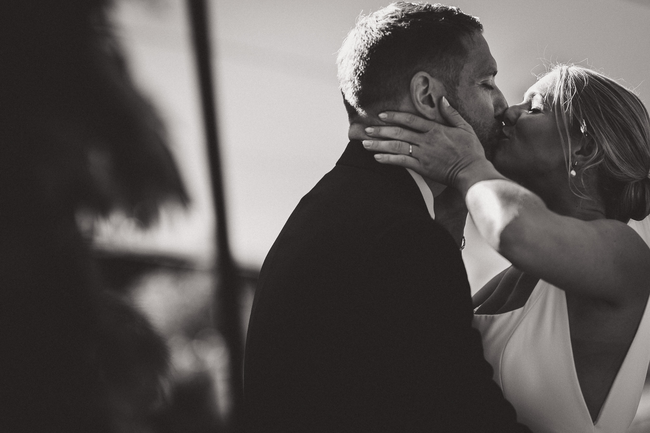 A black and white photo of a bride and groom sharing a kiss, captured by a wedding photographer.