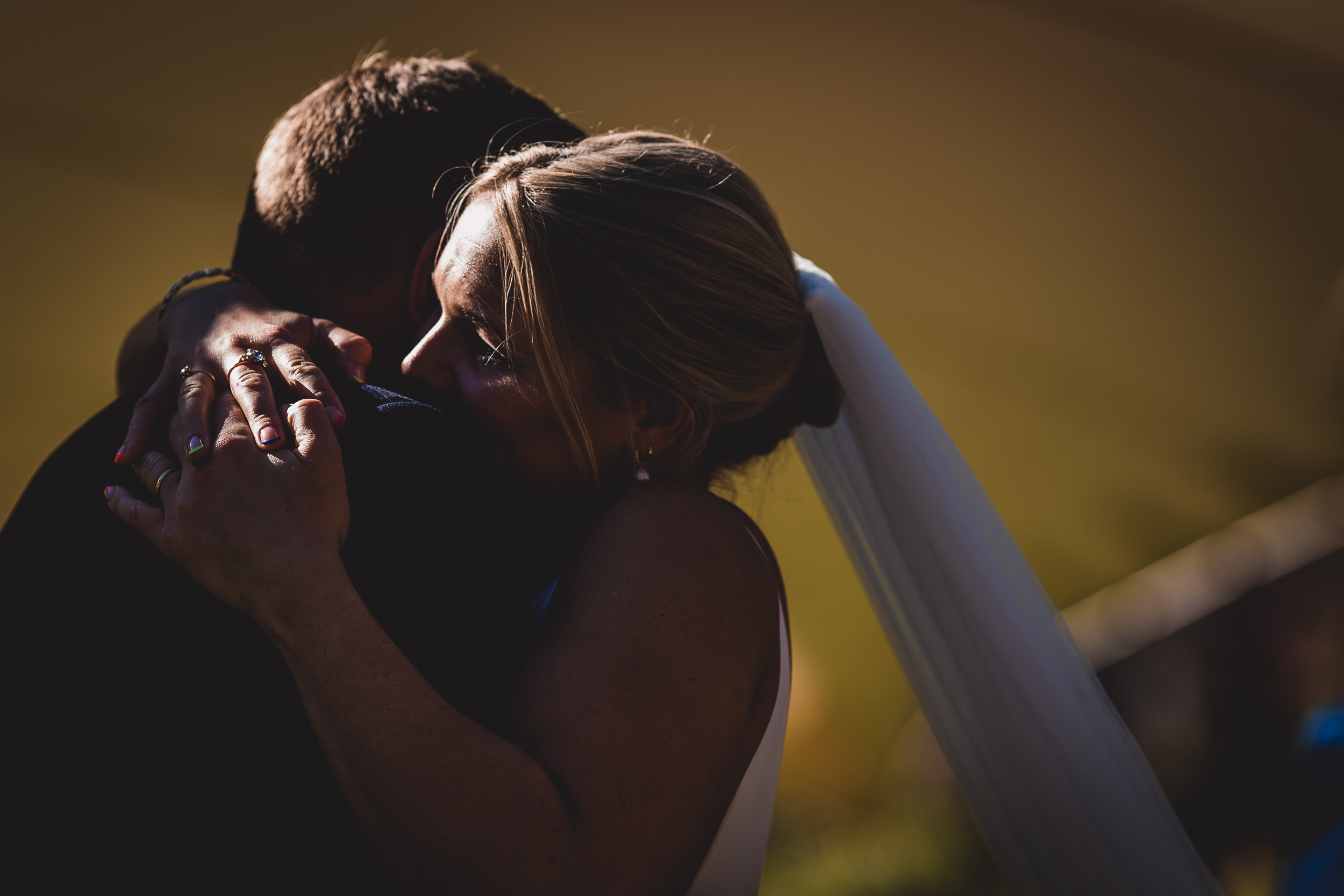 A wedding couple embracing beside a tent.