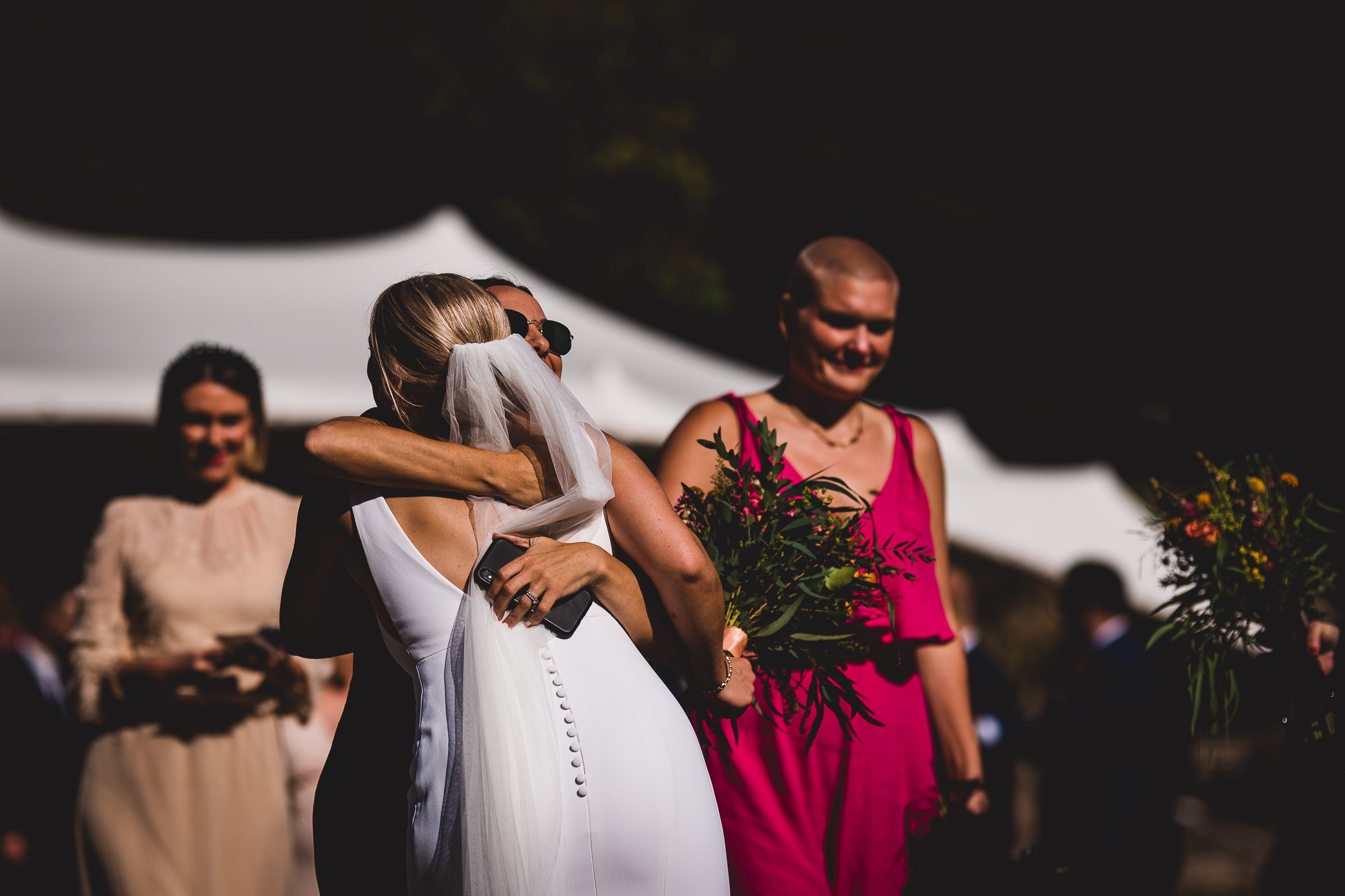 A bride is hugging her bridesmaids as they walk down the wedding aisle.