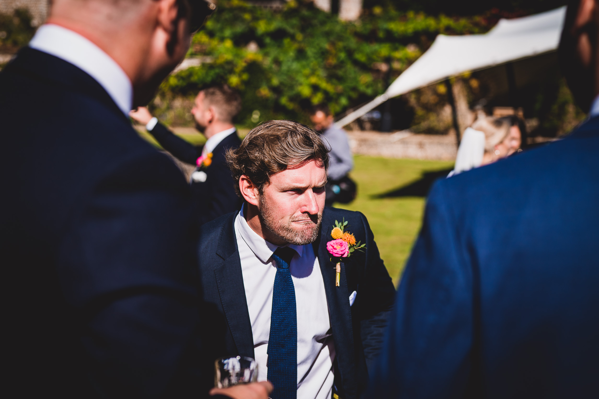 A man in a suit is talking to another man in a suit at a wedding.