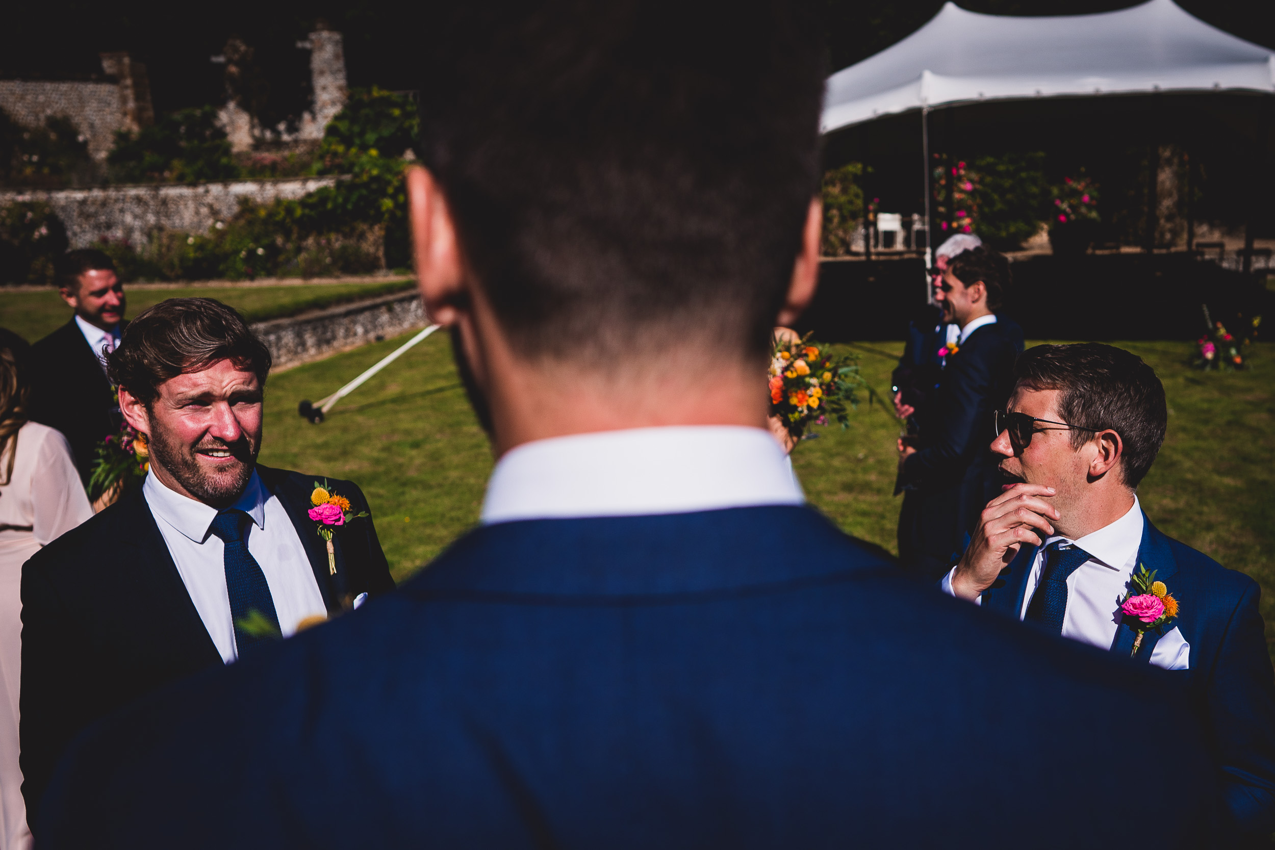 A man in a suit is looking at another man in a suit during a wedding.