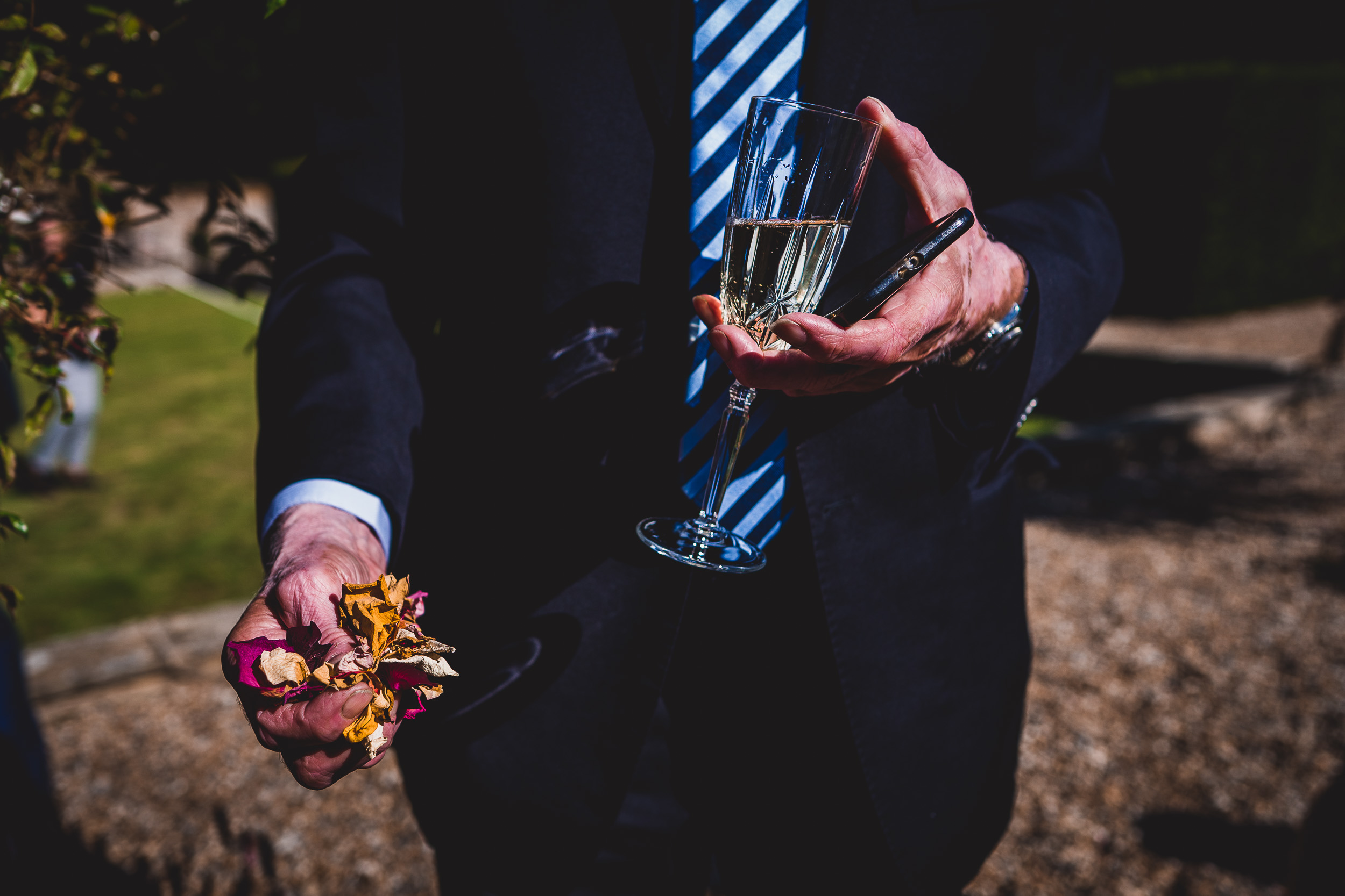 A groom in a suit holding a glass of champagne.