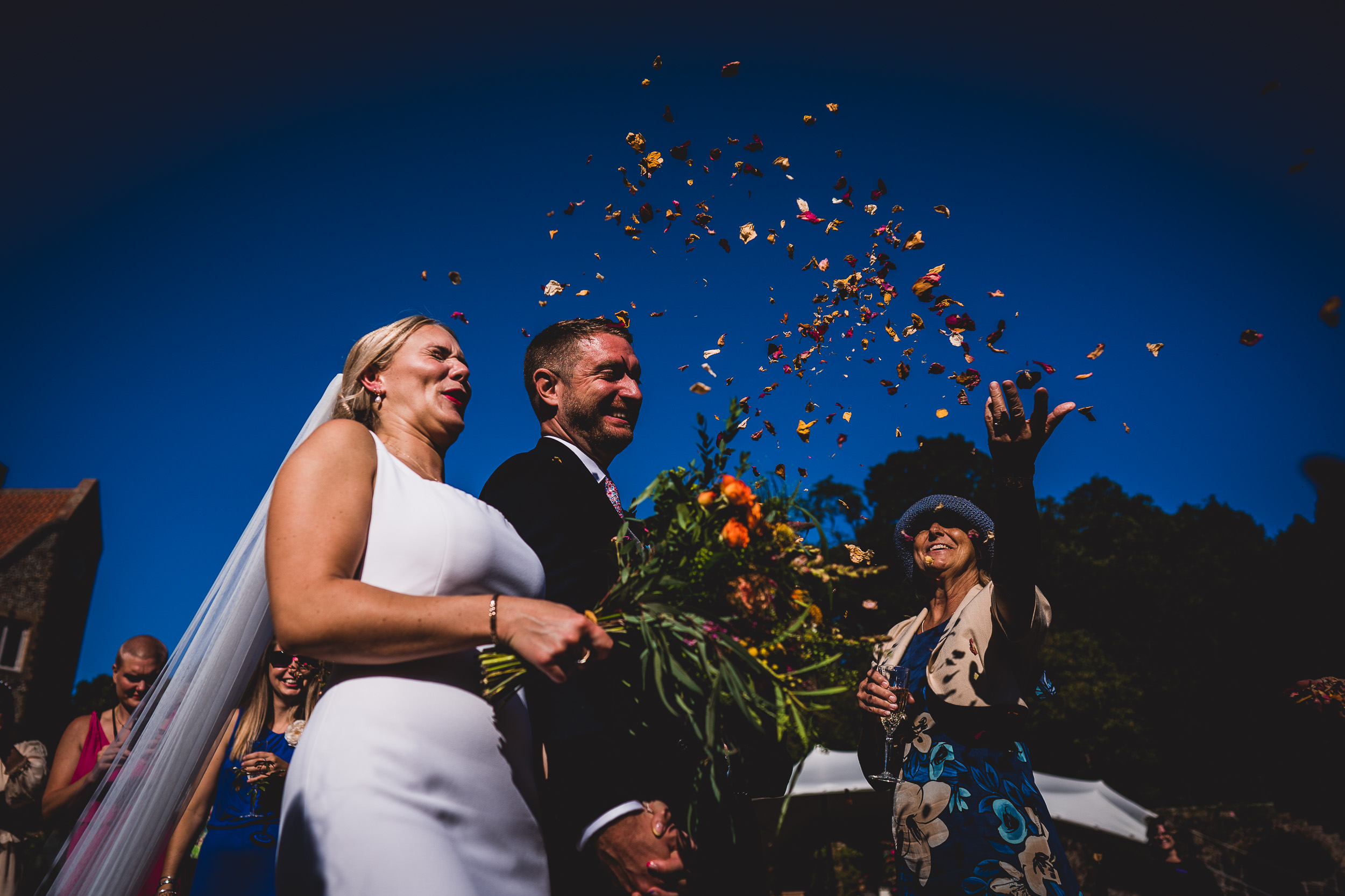 A wedding couple captured by a wedding photographer throwing confetti during their wedding photo session.