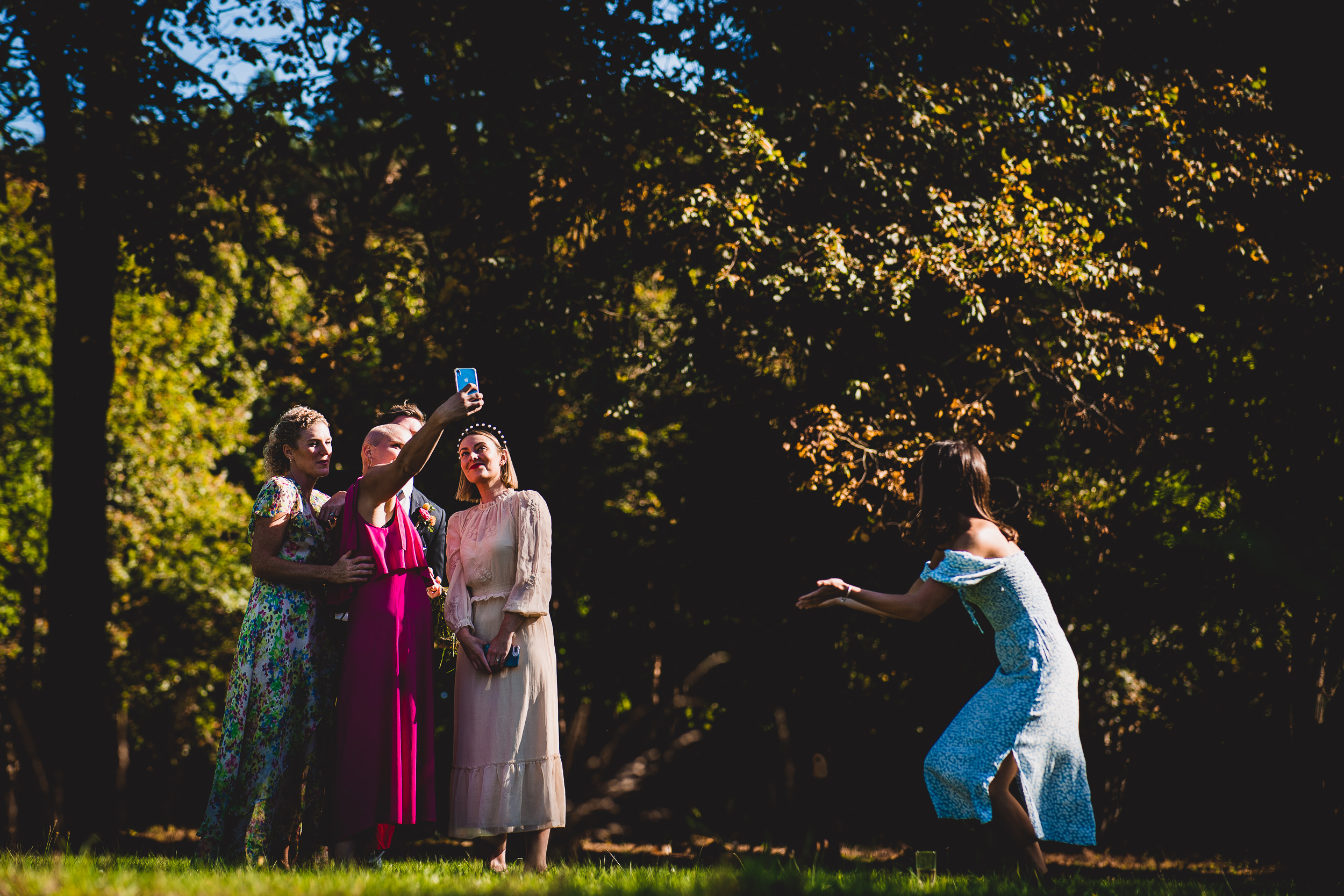 A group of bridesmaids capturing a wedding photo in the woods.