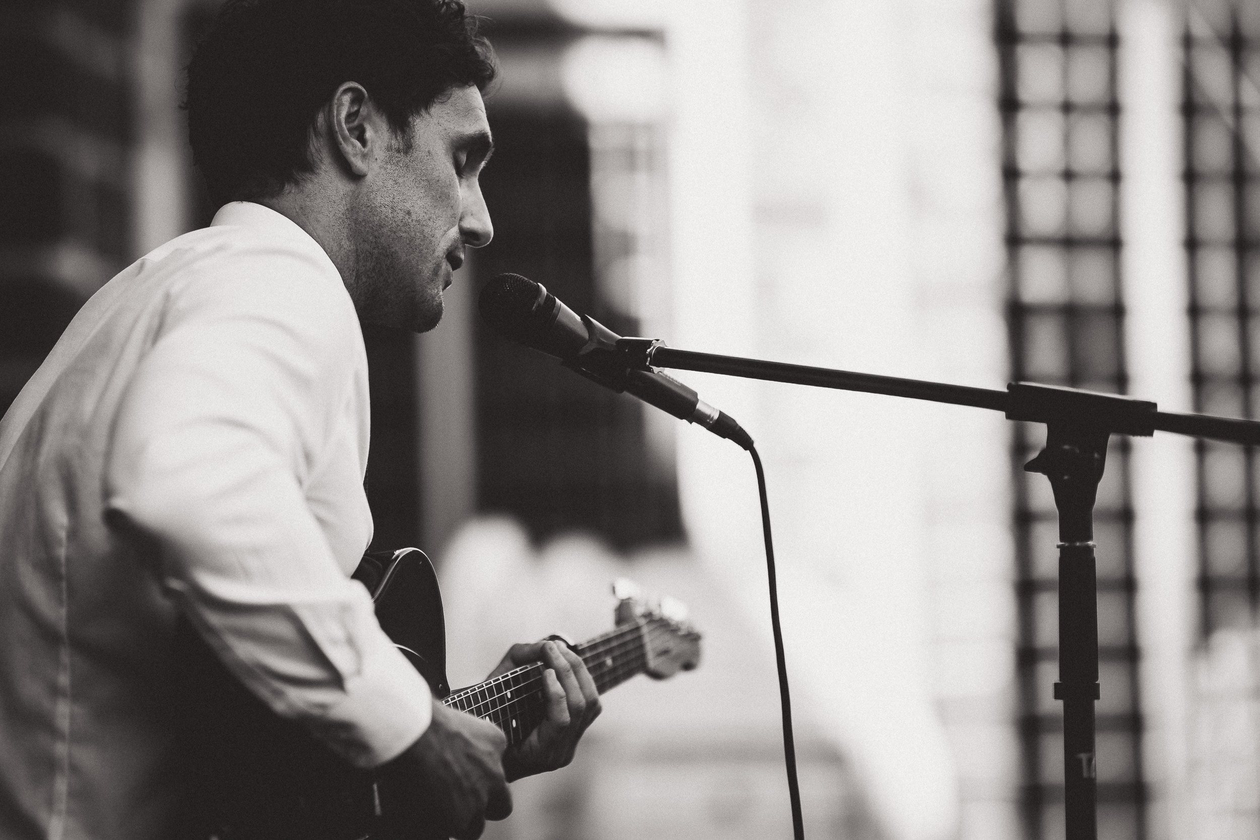 A groom playing a guitar during a wedding photo shoot.