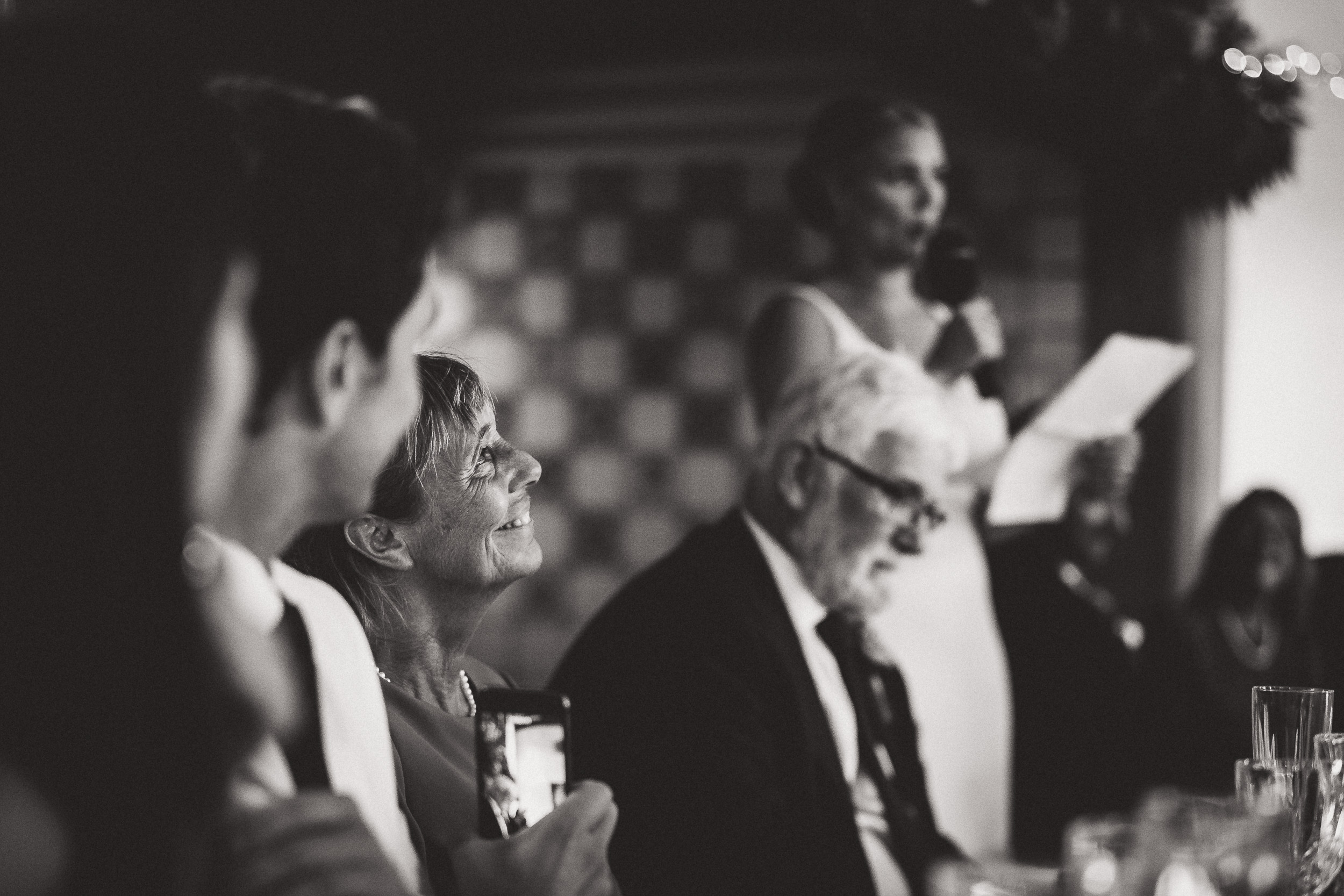 Black and white photo of a bride giving a speech at her wedding.