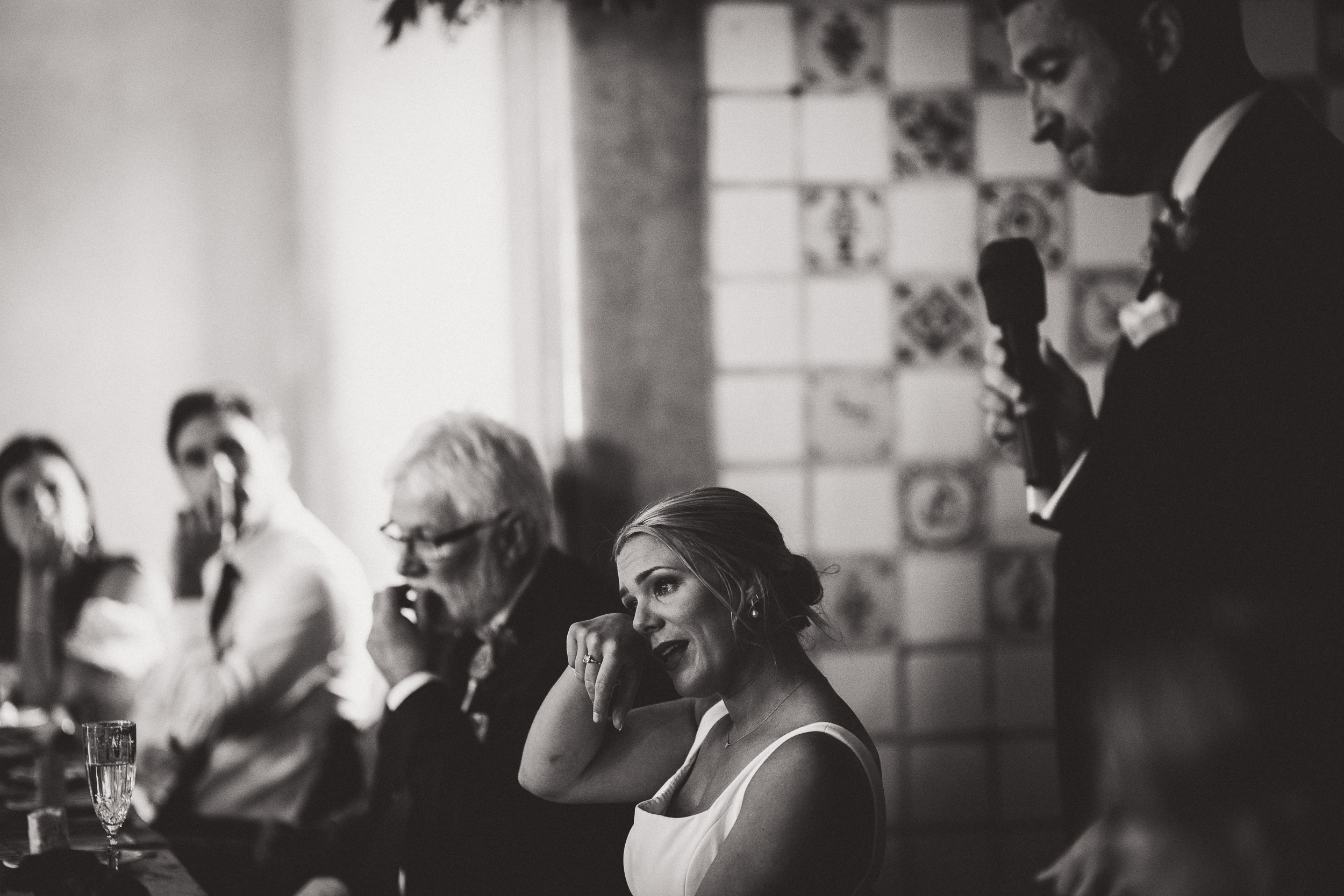 At a wedding, the bride confidently speaks into a microphone.