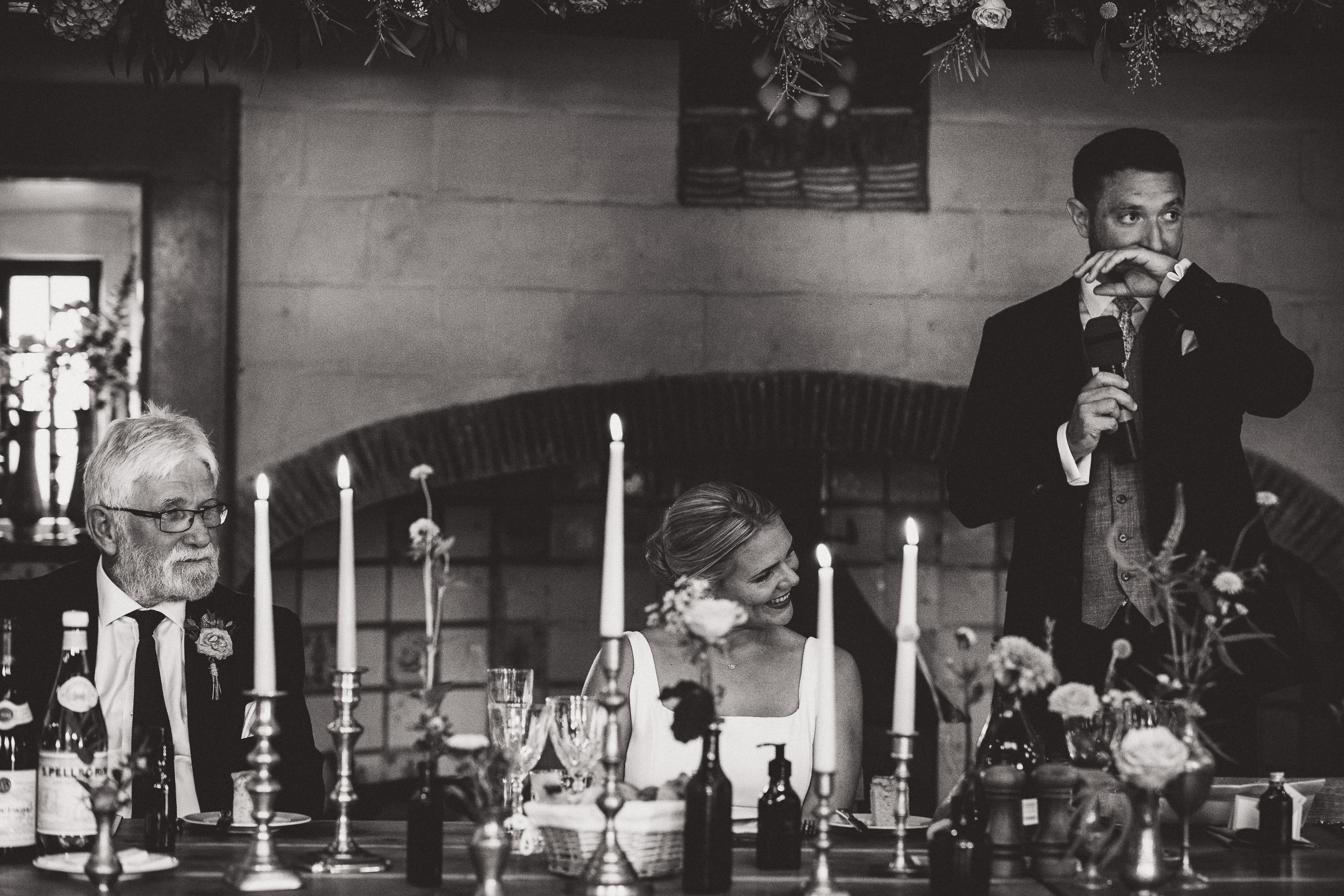 A wedding photographer captures the bride and groom at a beautifully decorated table adorned with candles.