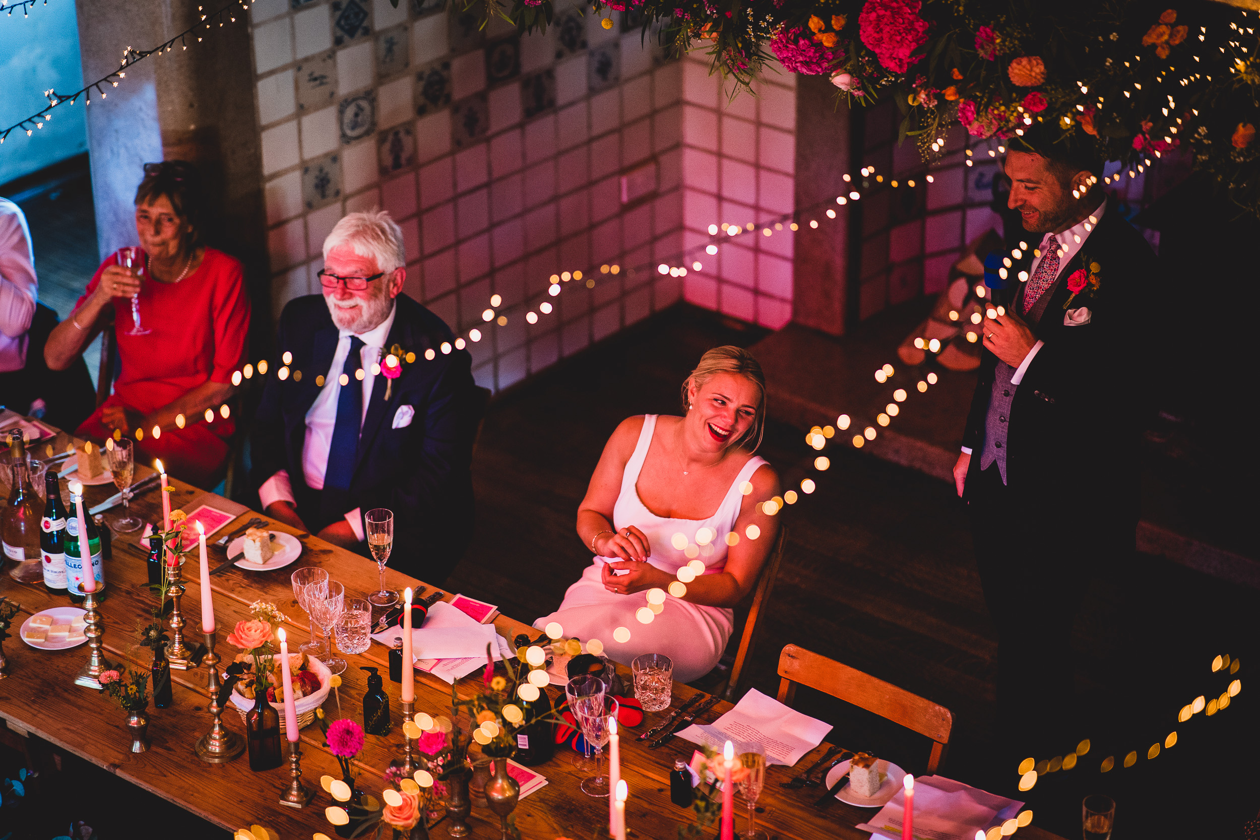 A bride and groom pose for a wedding photographer during their reception.