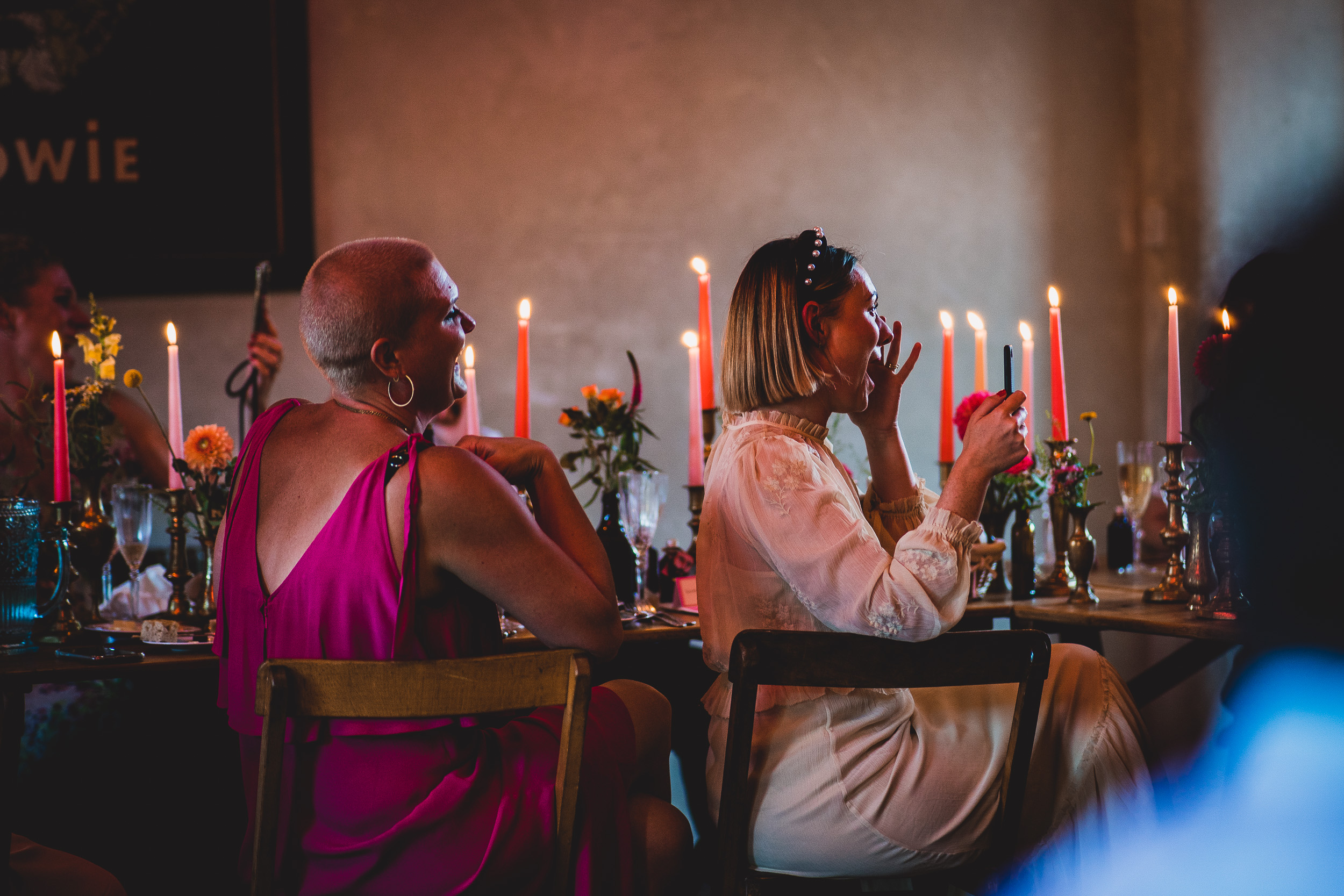 A bride sits at a table with candles in front of her, captured by a wedding photographer.