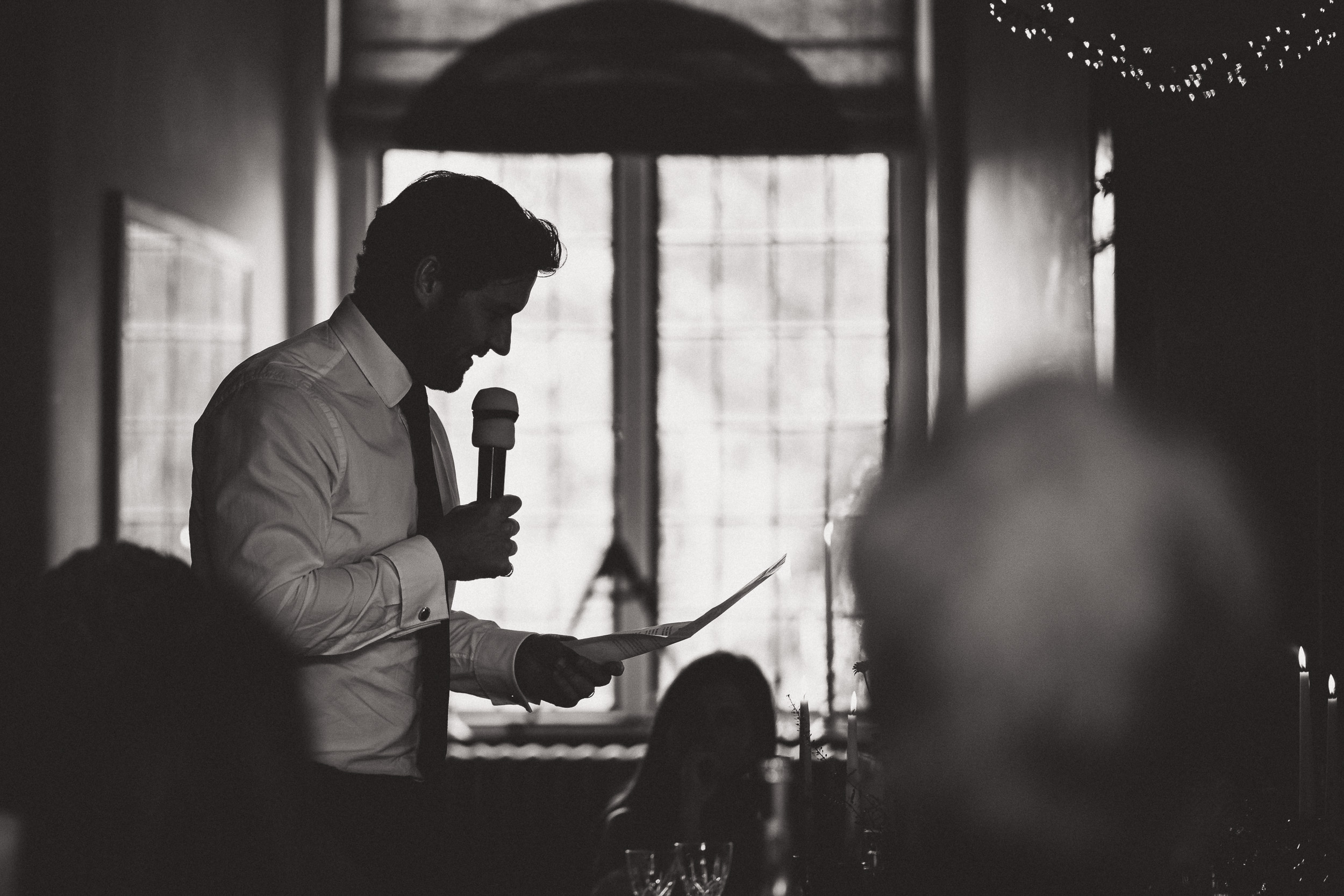 A man giving a speech at a wedding, captured by the wedding photographer.