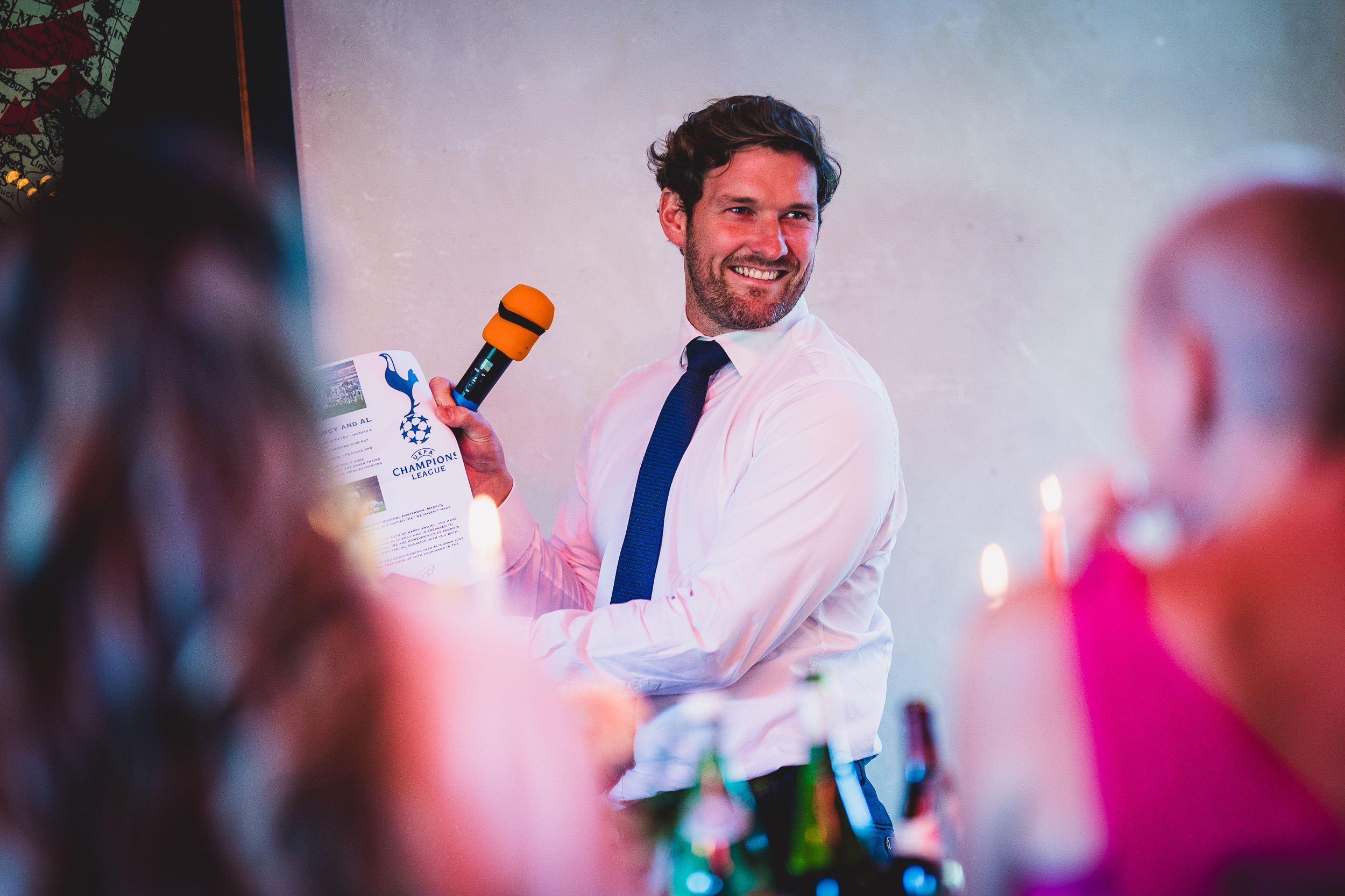 A man delivering a speech at a wedding ceremony, captured by the wedding photographer.