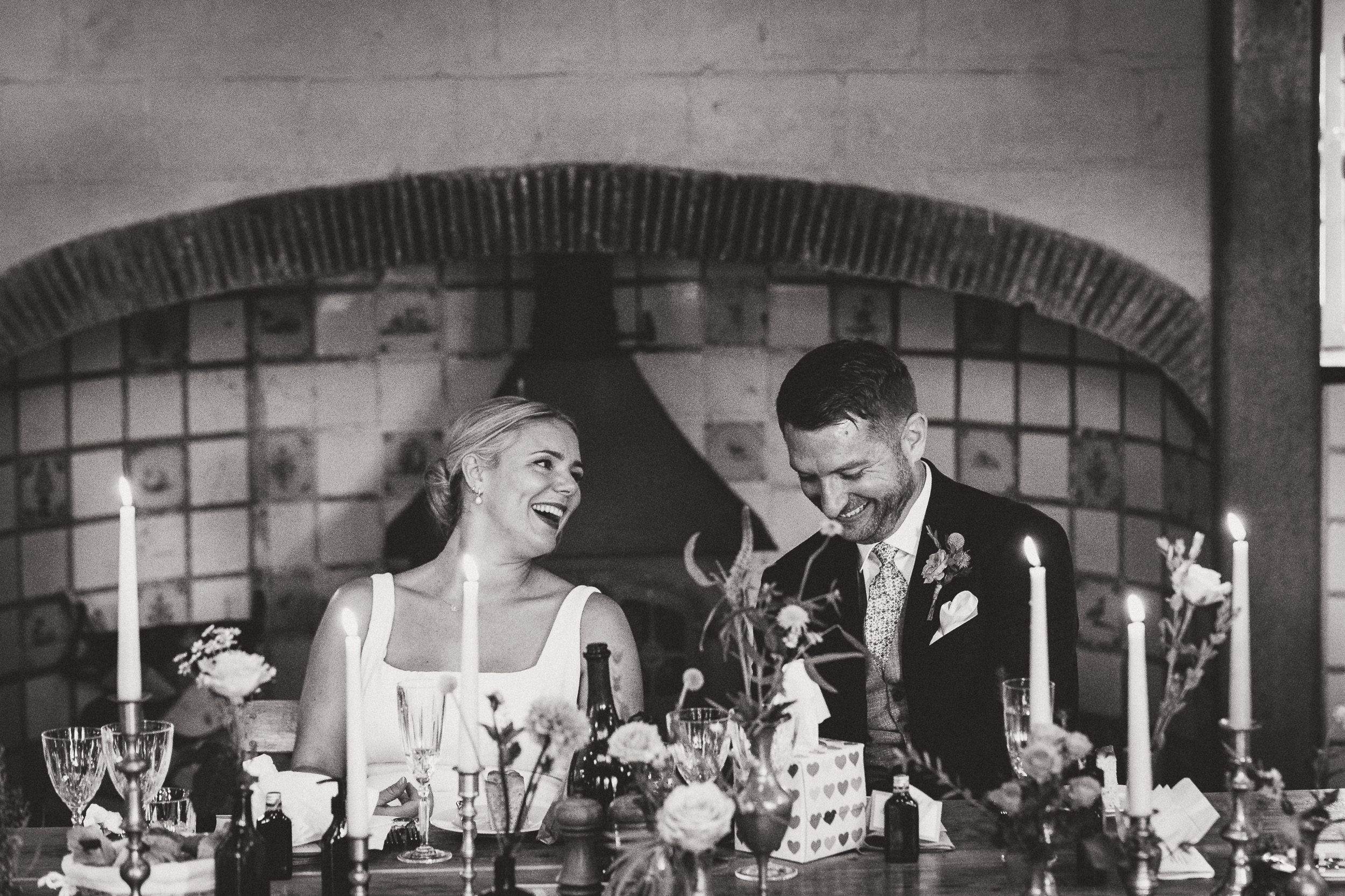 A wedding couple seated at a table adorned with candles.