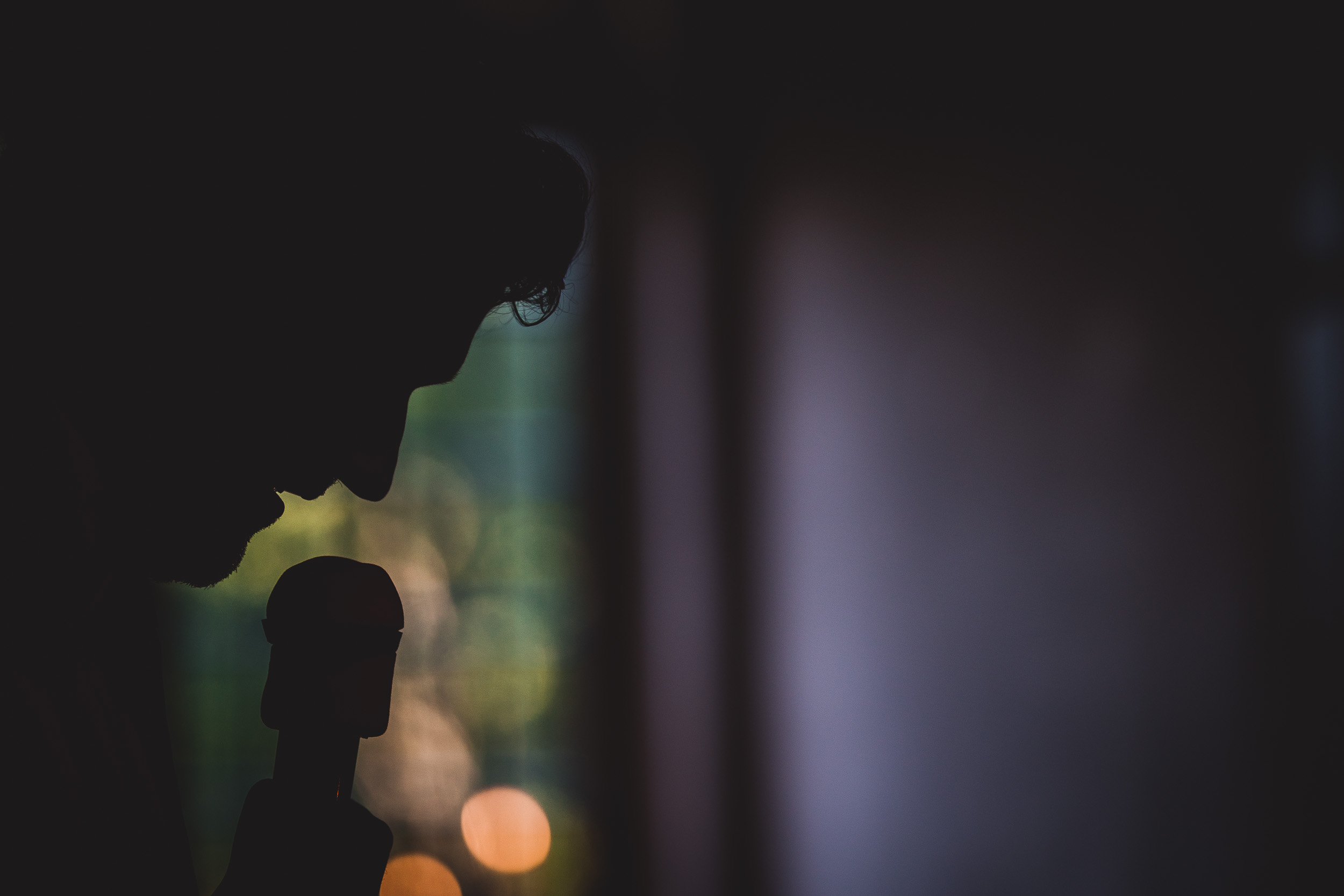 A silhouette of a man holding a microphone during a wedding ceremony.