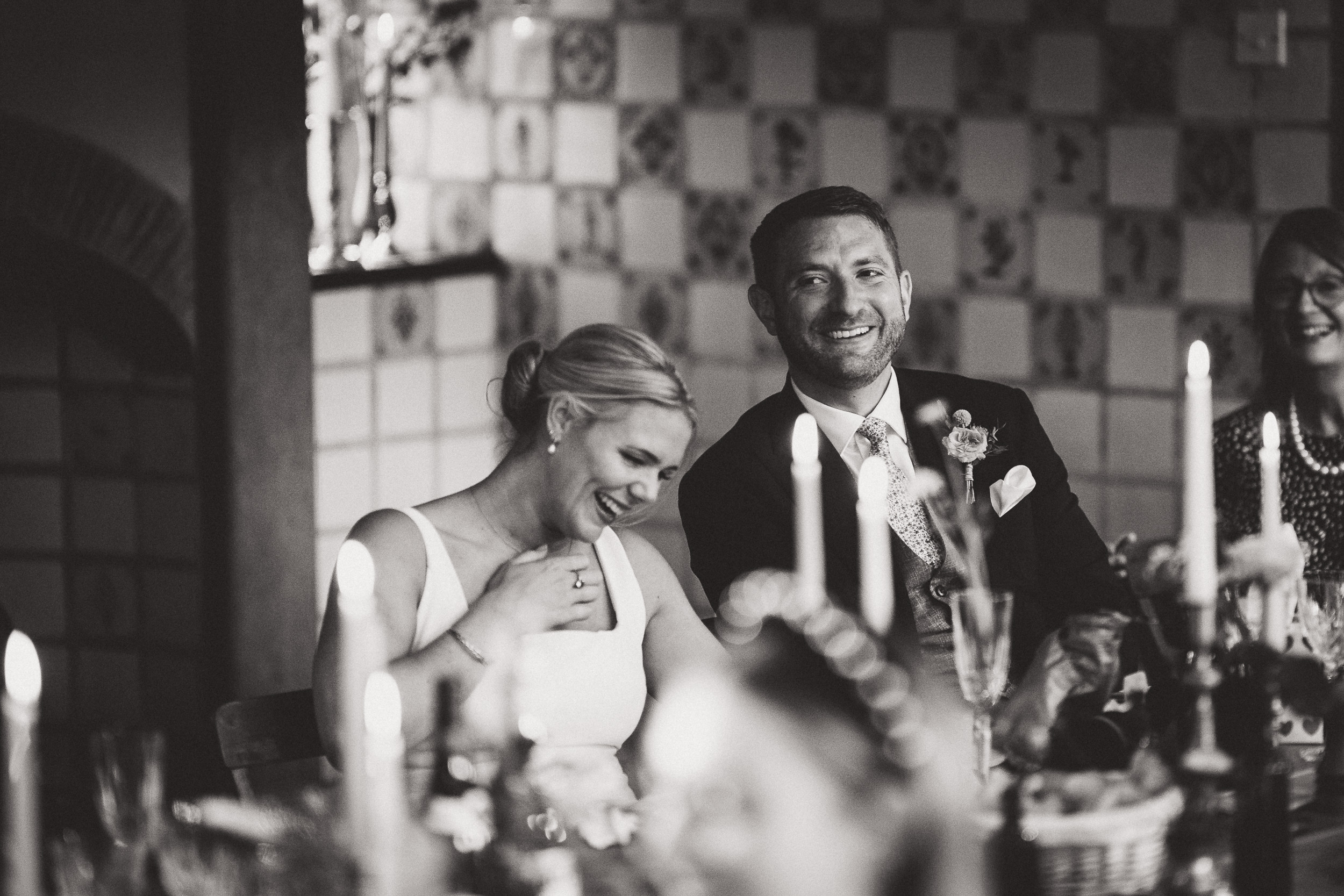 A wedding photo capturing the bride and groom seated at a table adorned with candles.