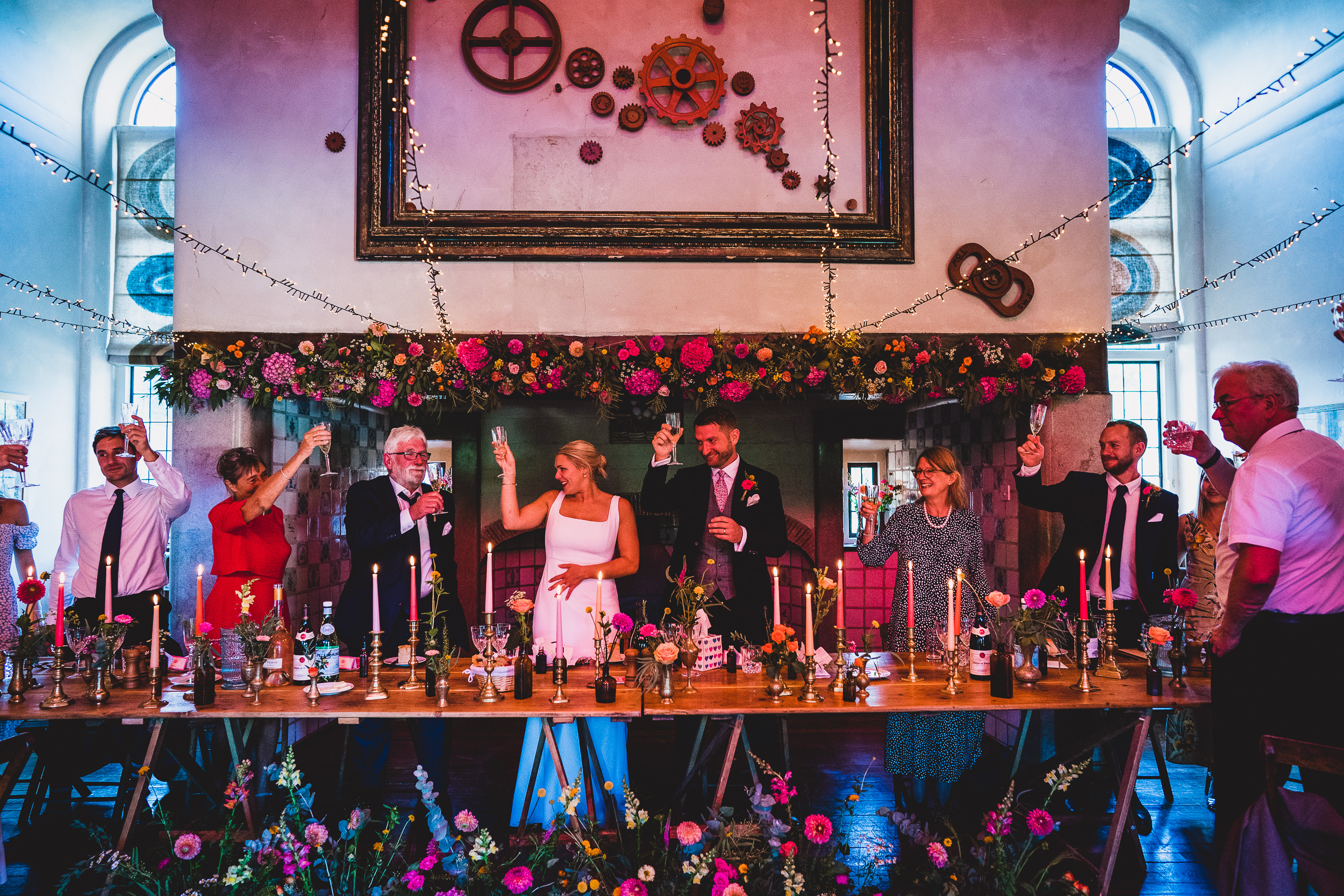 A Wedding photo with the groom and guests standing around a table.