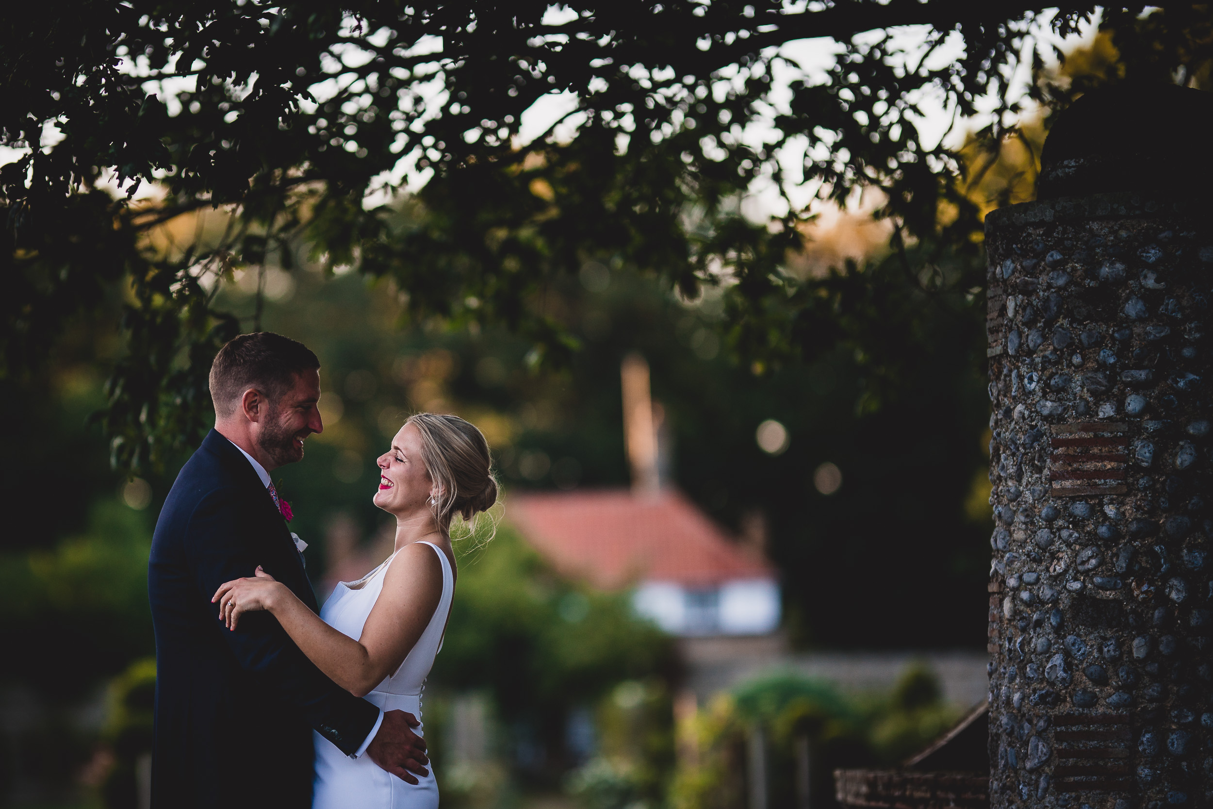 Wedding photo of a bride and groom embracing under a tree.