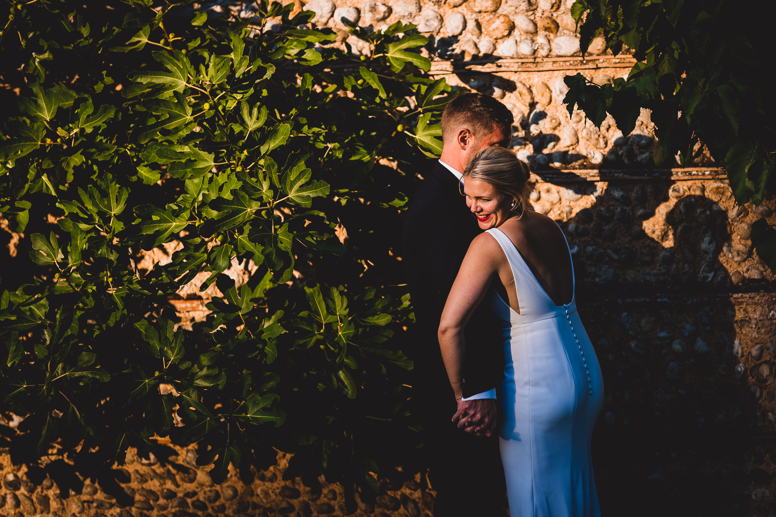 A bride and groom capturing a wedding photo in front of a wall.