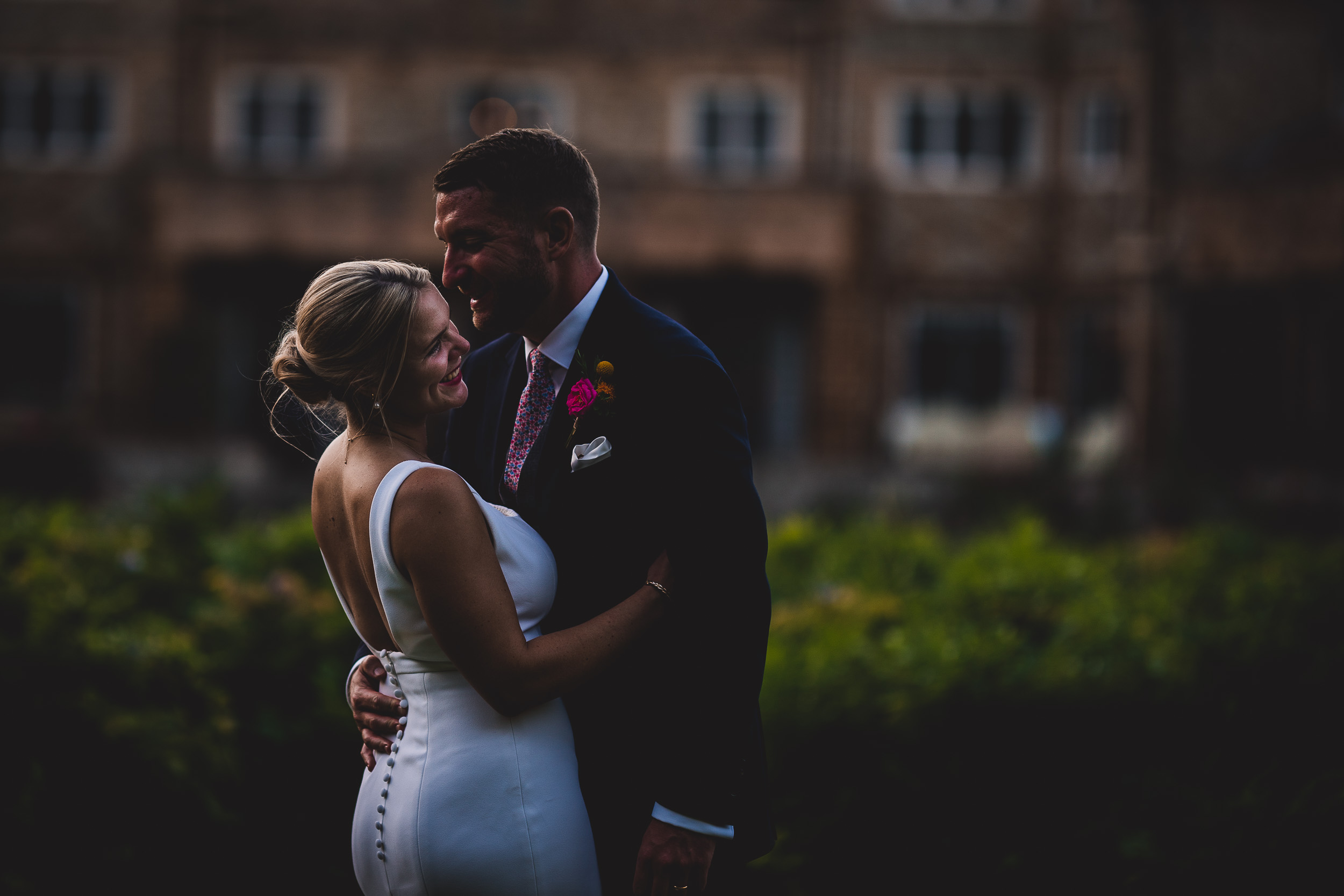 A bride and groom embracing in front of a building captured by a wedding photographer.