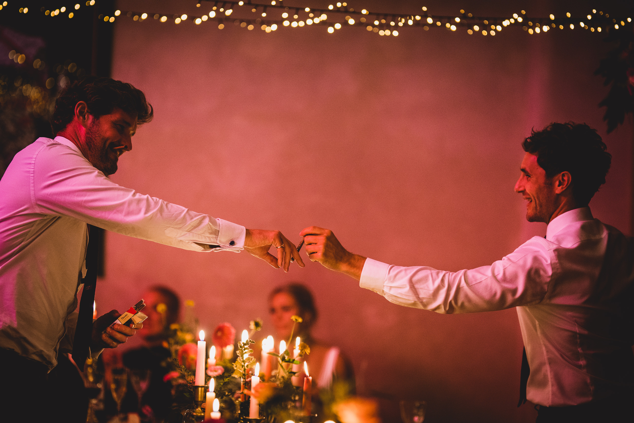 A groom and wedding photographer capture a sentimental moment of two men shaking hands at a wedding reception to create a cherished wedding photo.