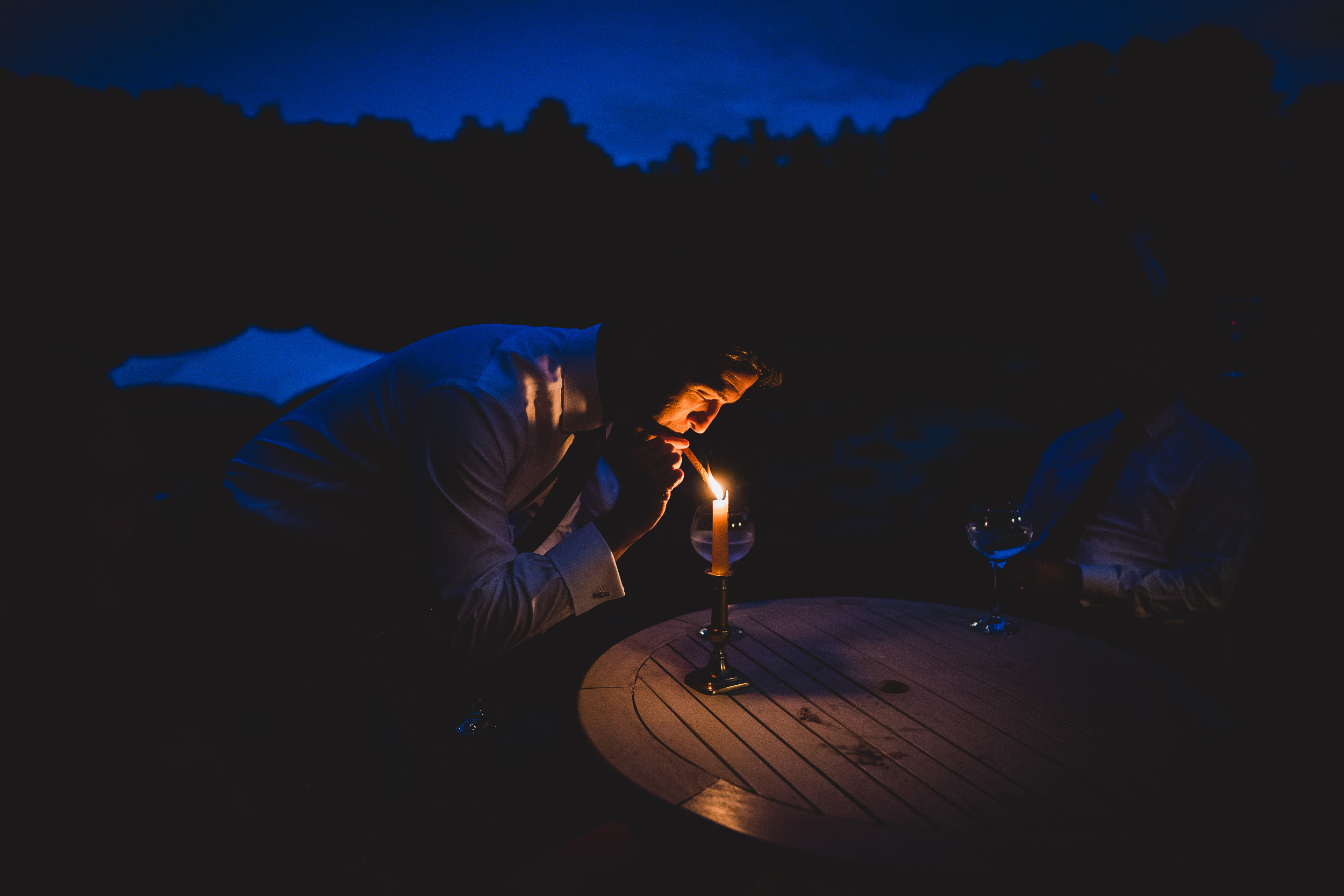 A groom lighting a candle at the wedding table.