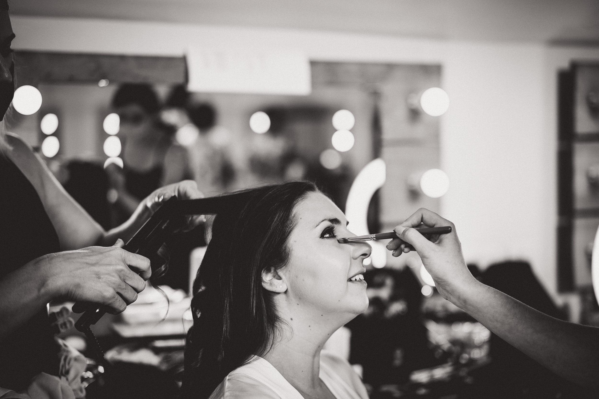 A bride getting her makeup done before her wedding.