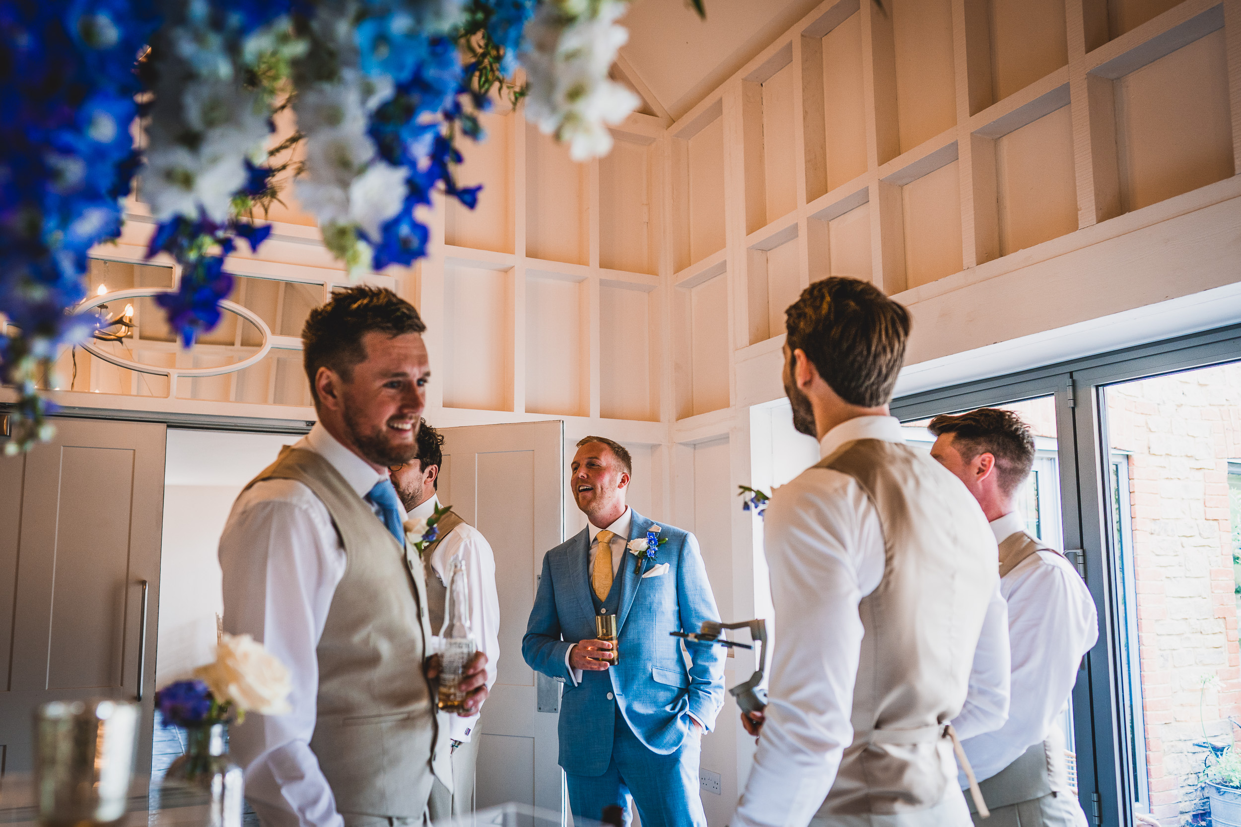 A group of groomsmen standing at a wedding with blue flowers.