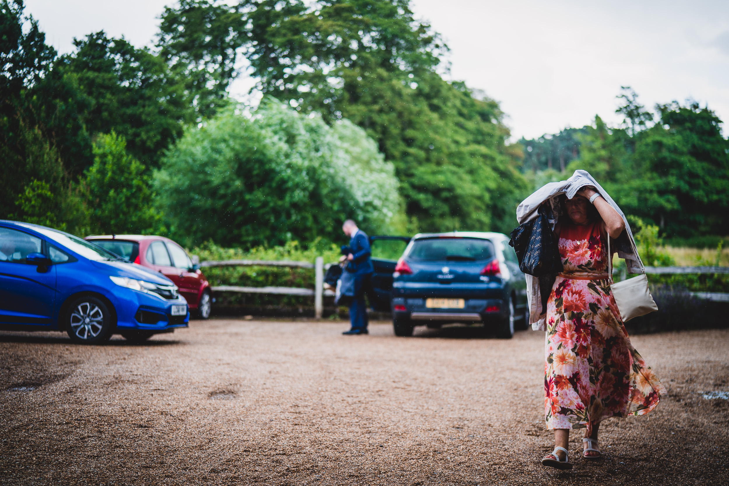 A bride walking down a dirt road with her umbrella for a wedding photo.