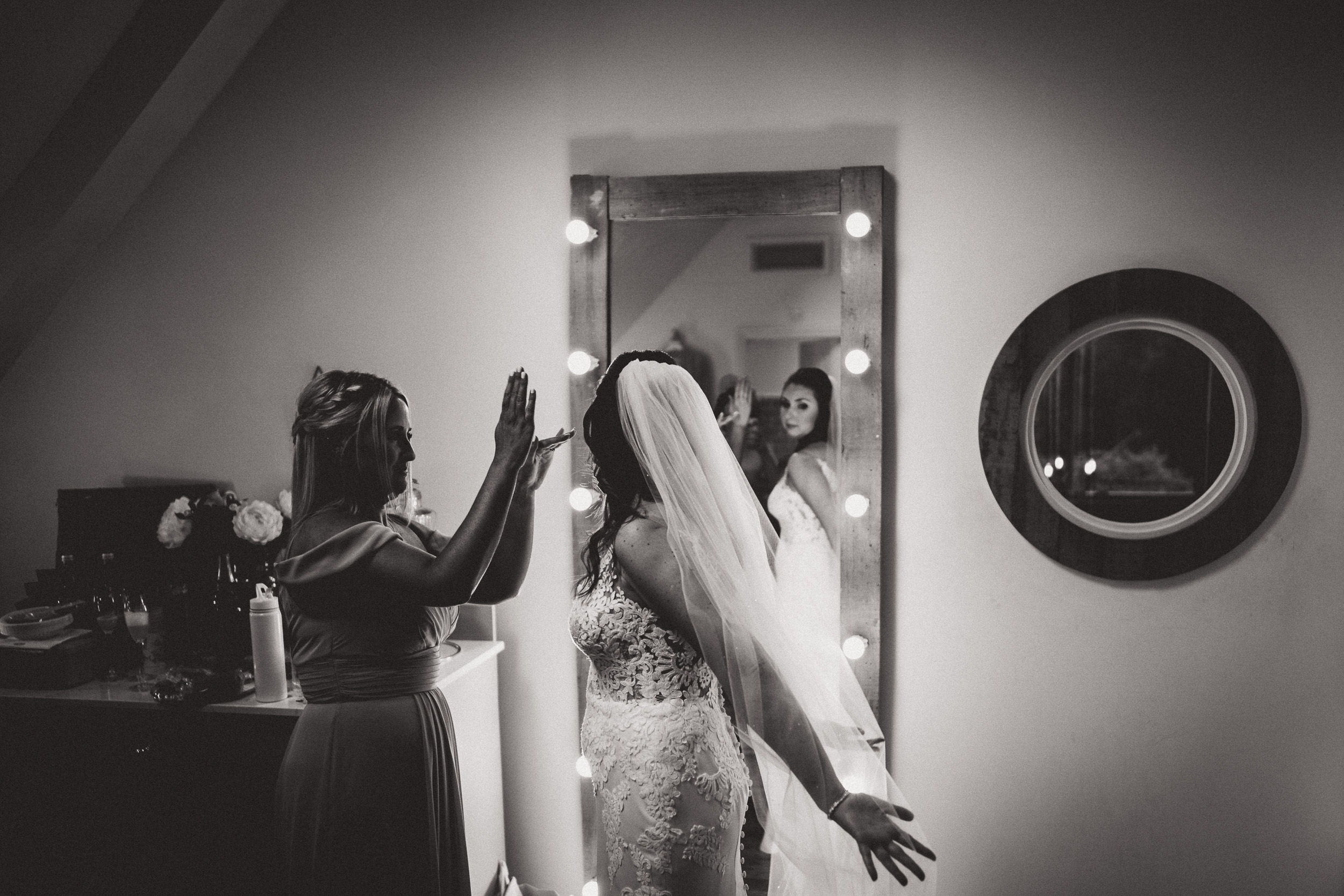 A bride getting ready in front of a mirror, captured by a wedding photographer.