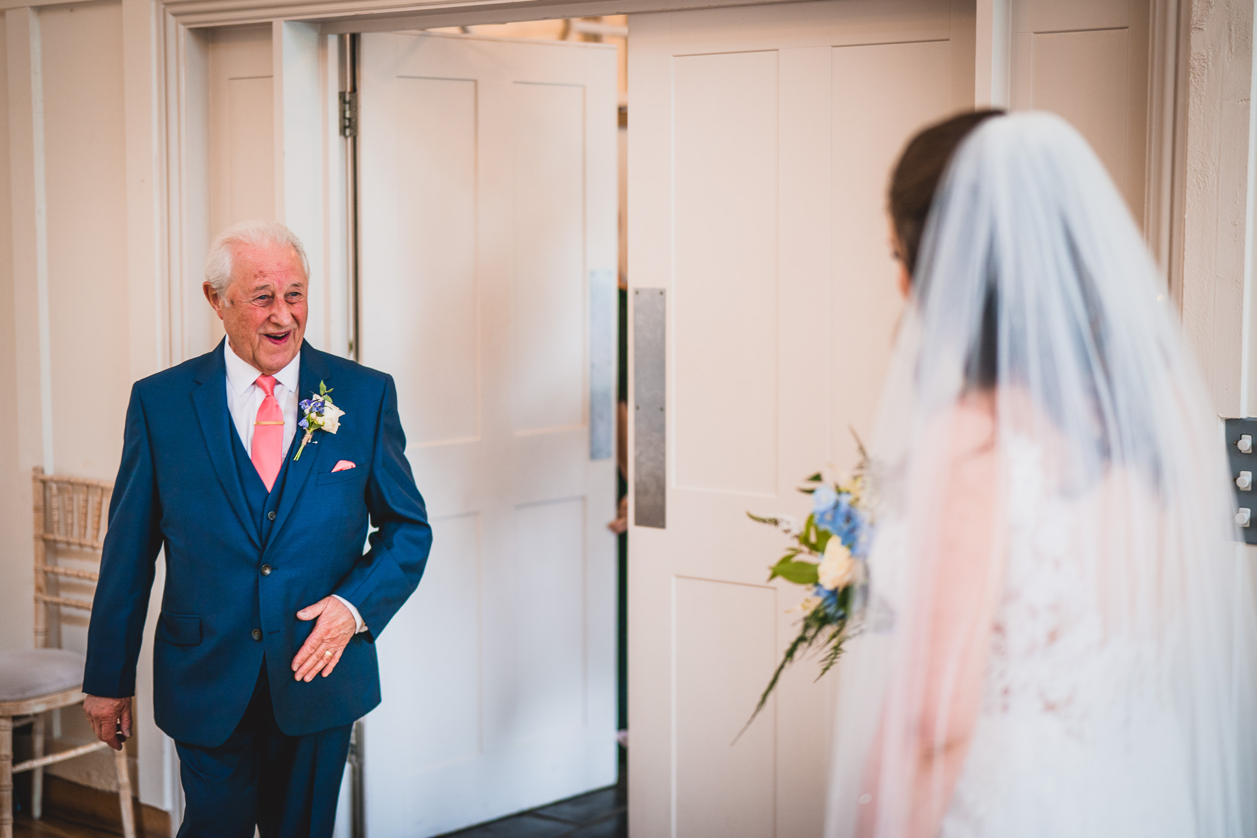 A groom in a suit walks into a room with a bride.