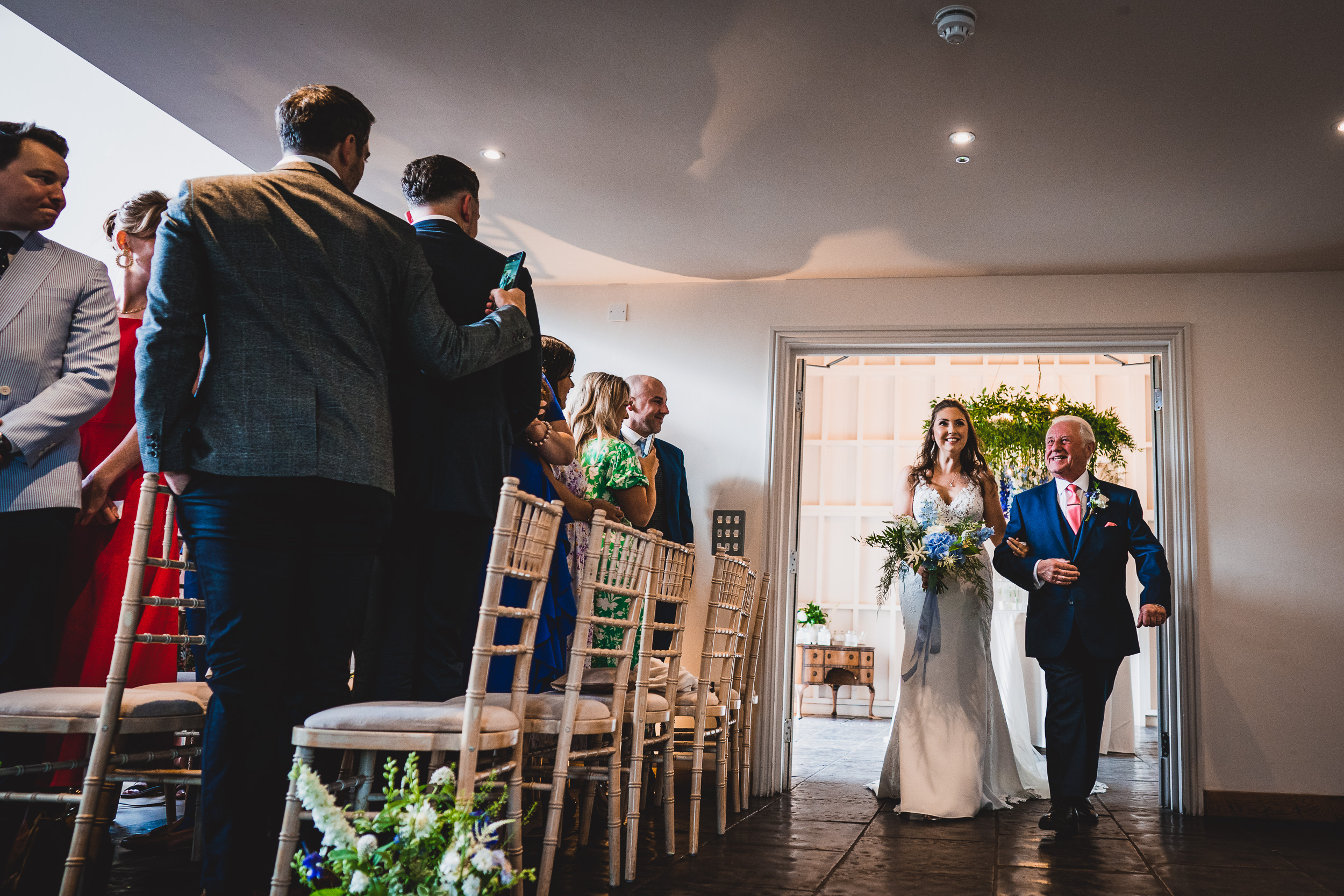 A wedding photo captures the bride walking down the aisle with her father.