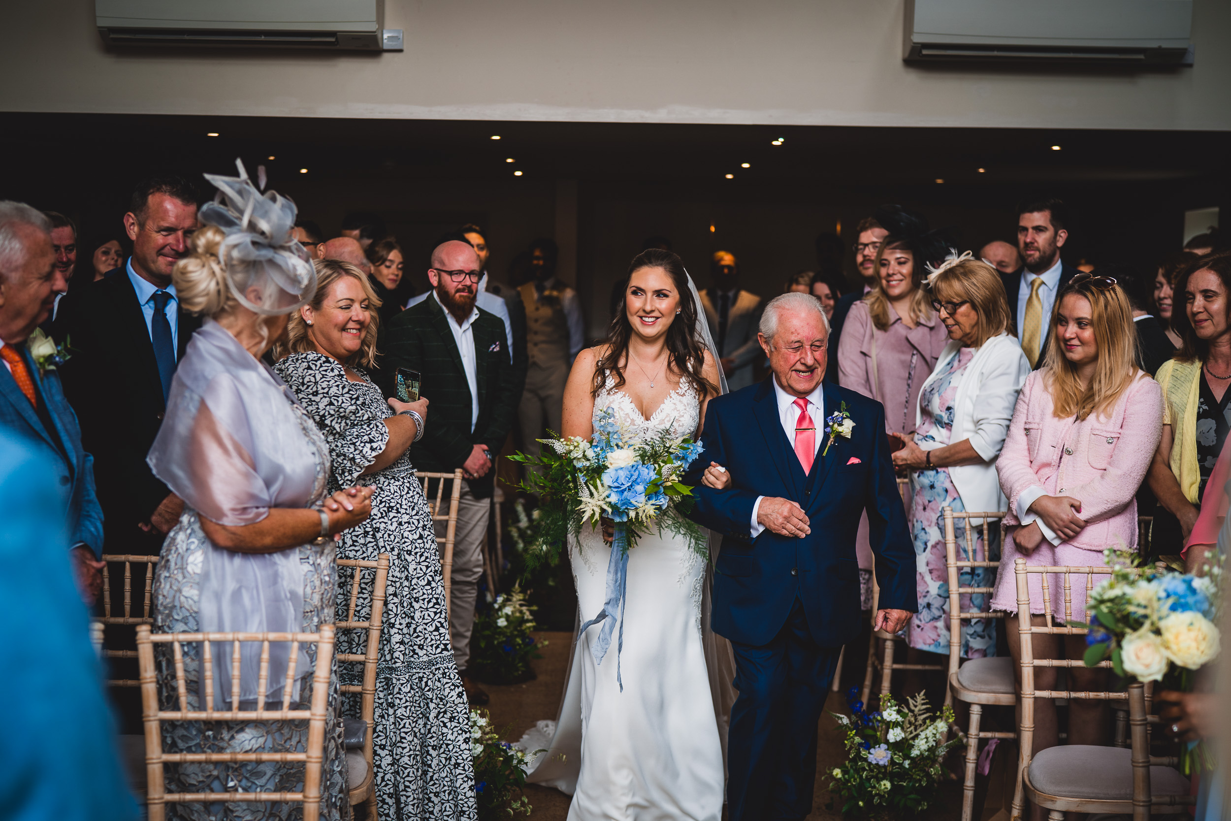 A bride walking down the aisle with her father captured by the wedding photographer.