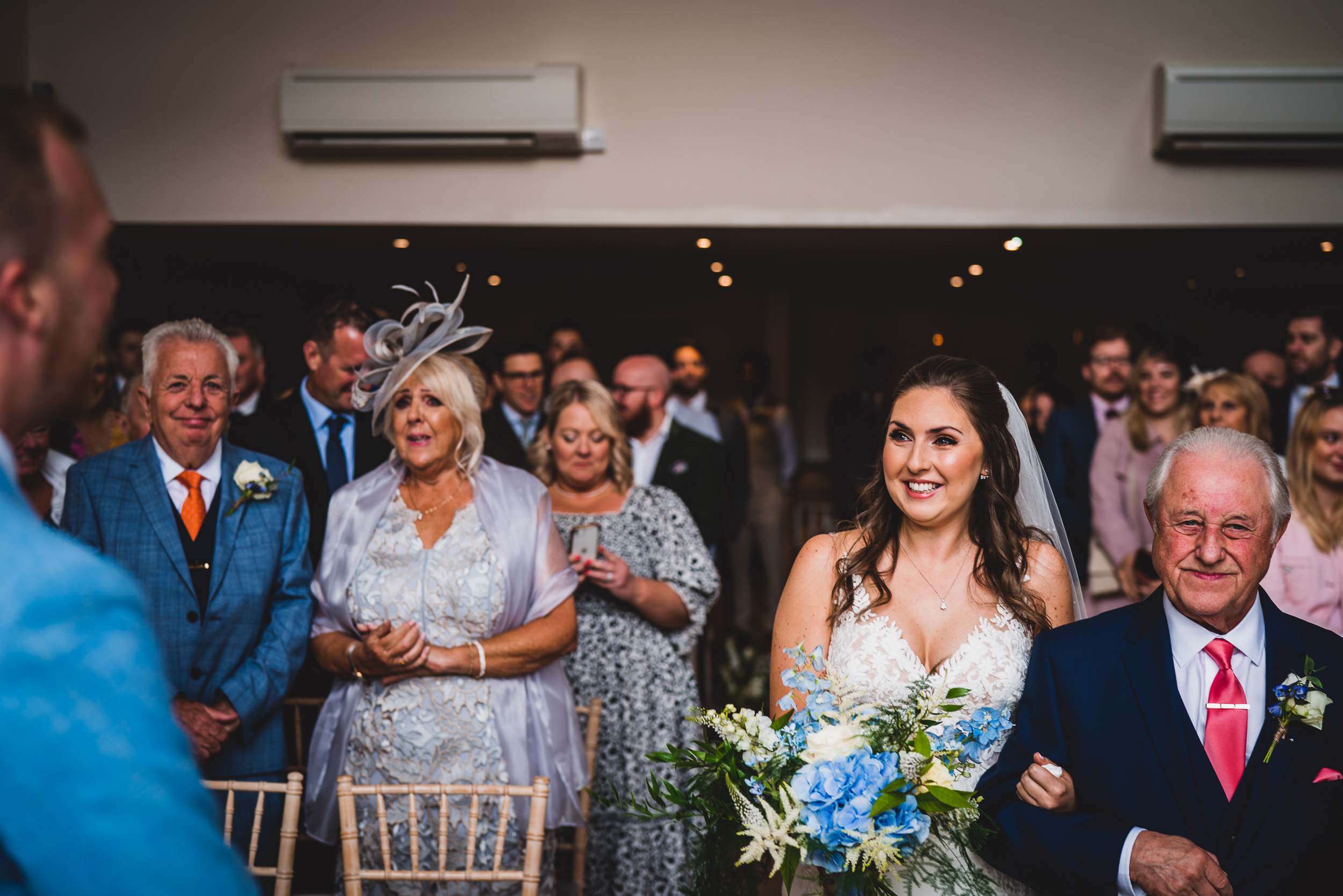 A wedding photo captures the bride walking down the aisle with her father.