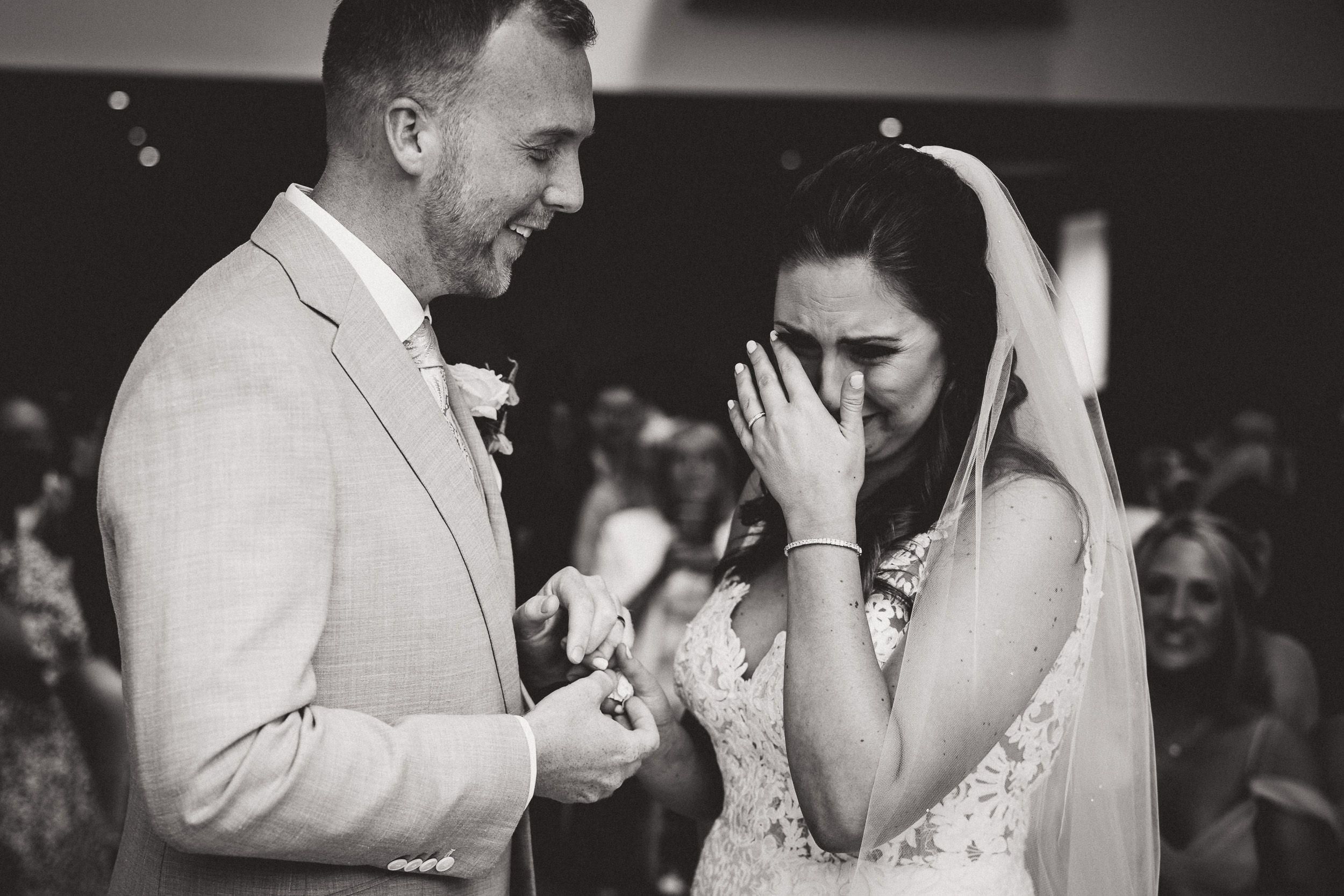 A groom laughing at the bride during their wedding ceremony captured in a wedding photo.